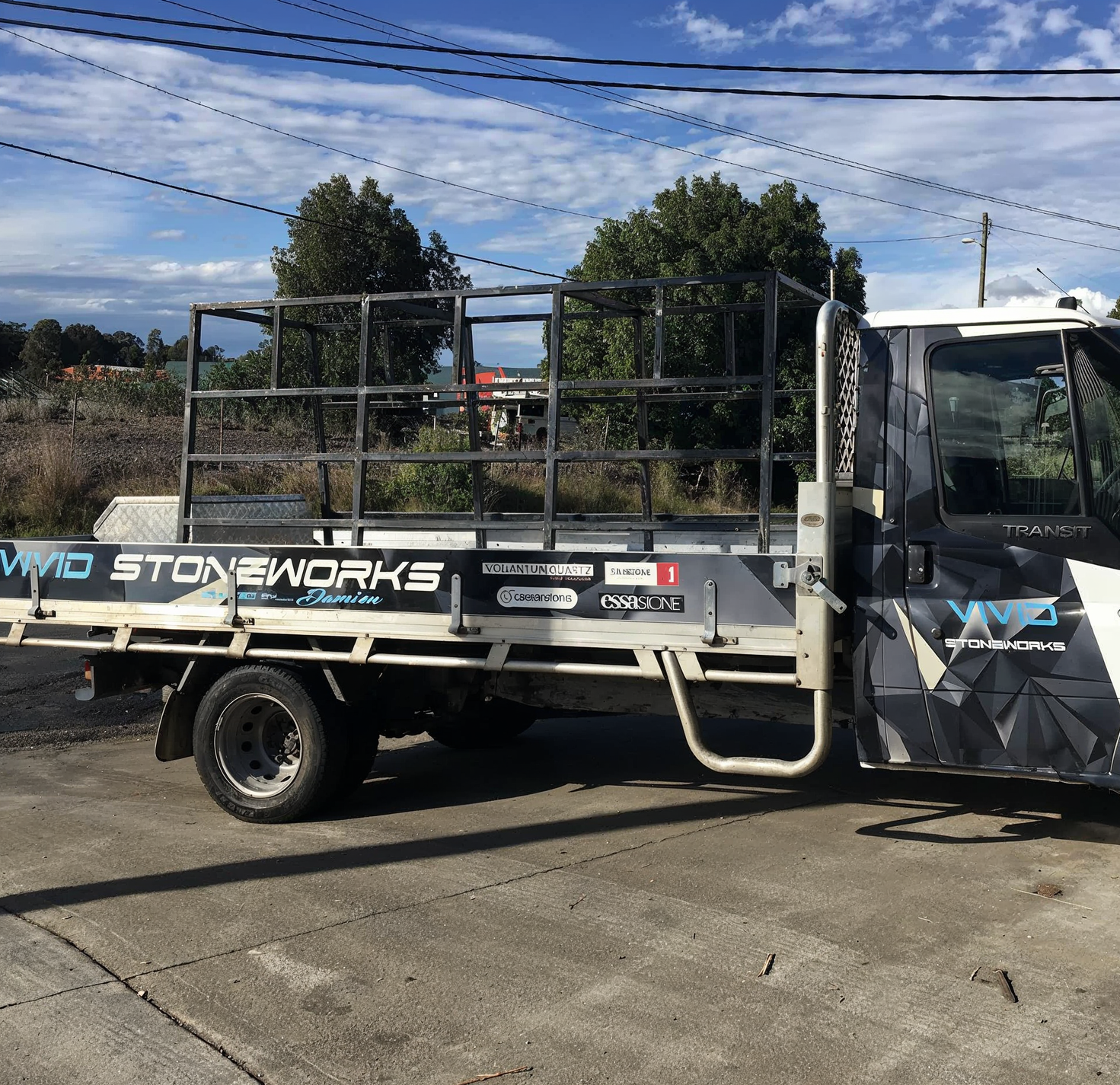 Flatbed work truck with metal racks parked outdoors under a blue sky