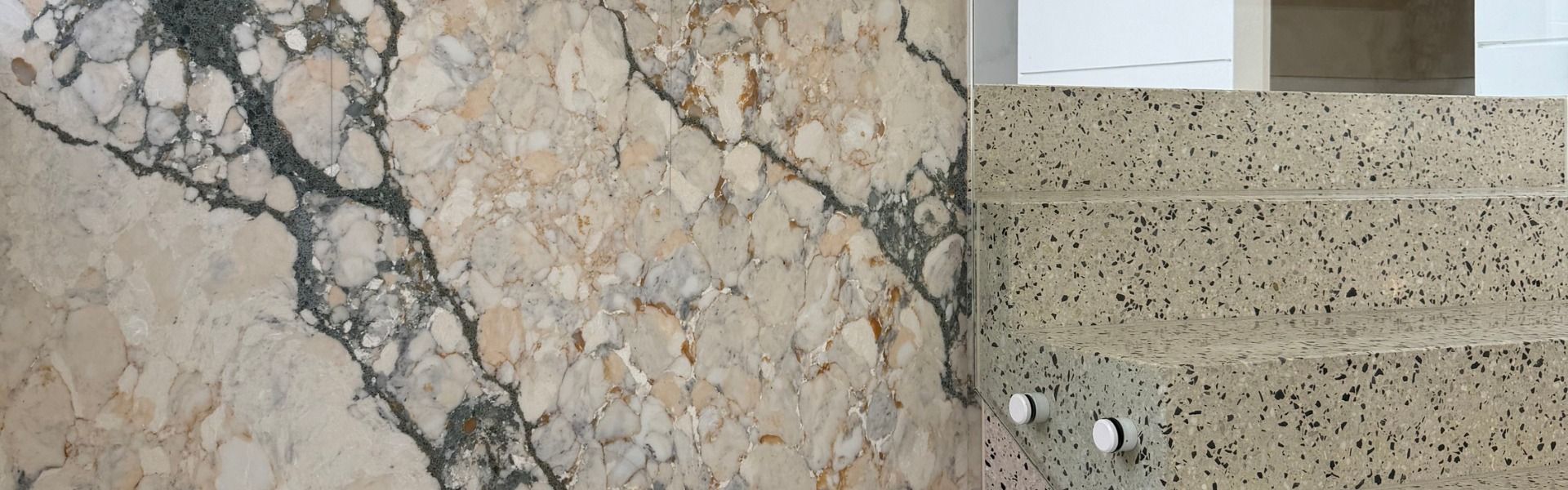 Split image showing marble and speckled stone countertops with a window and sink area