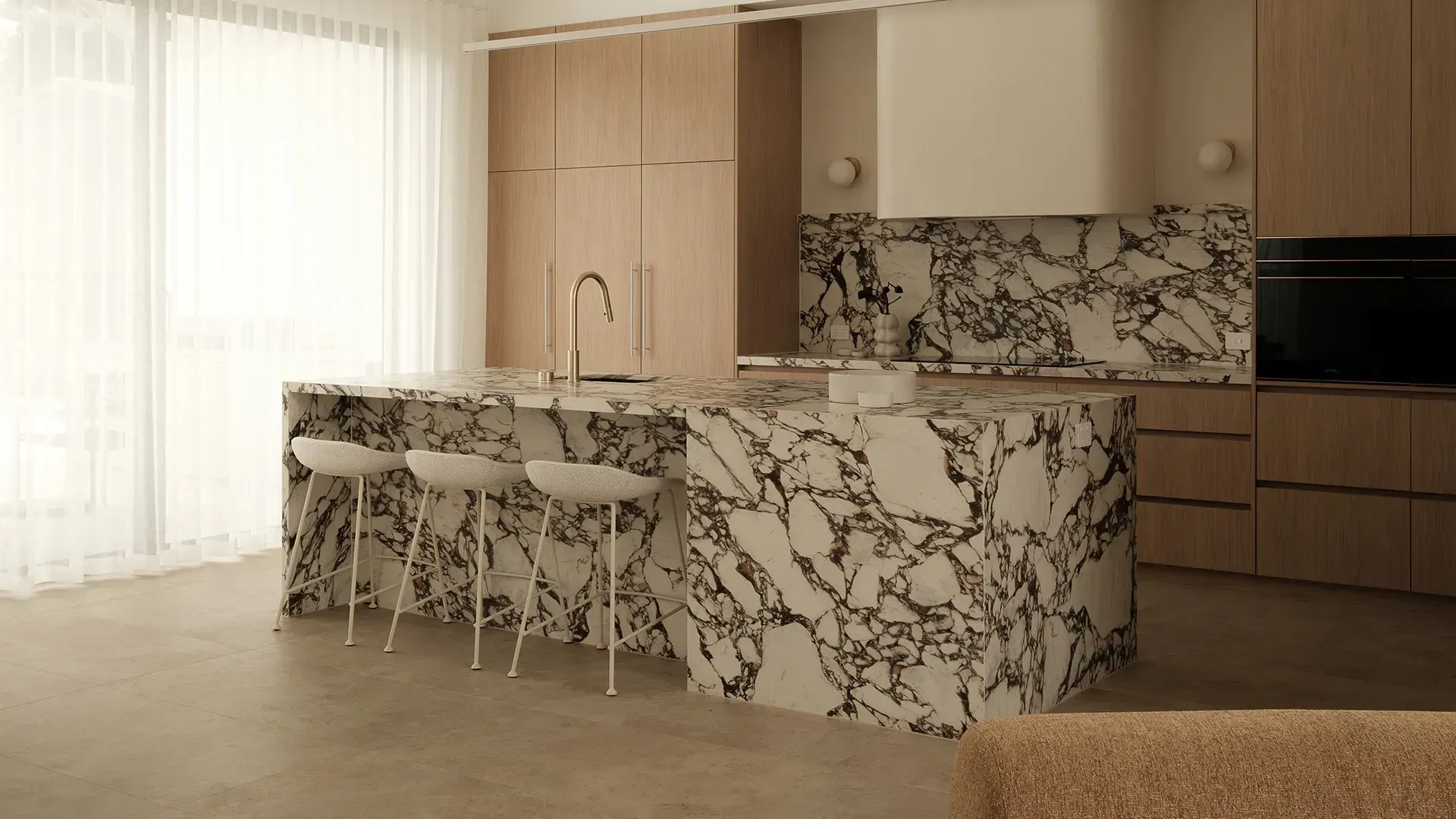Modern kitchen with marble-patterned island, bar stools, wood cabinets, and bright sheer curtains