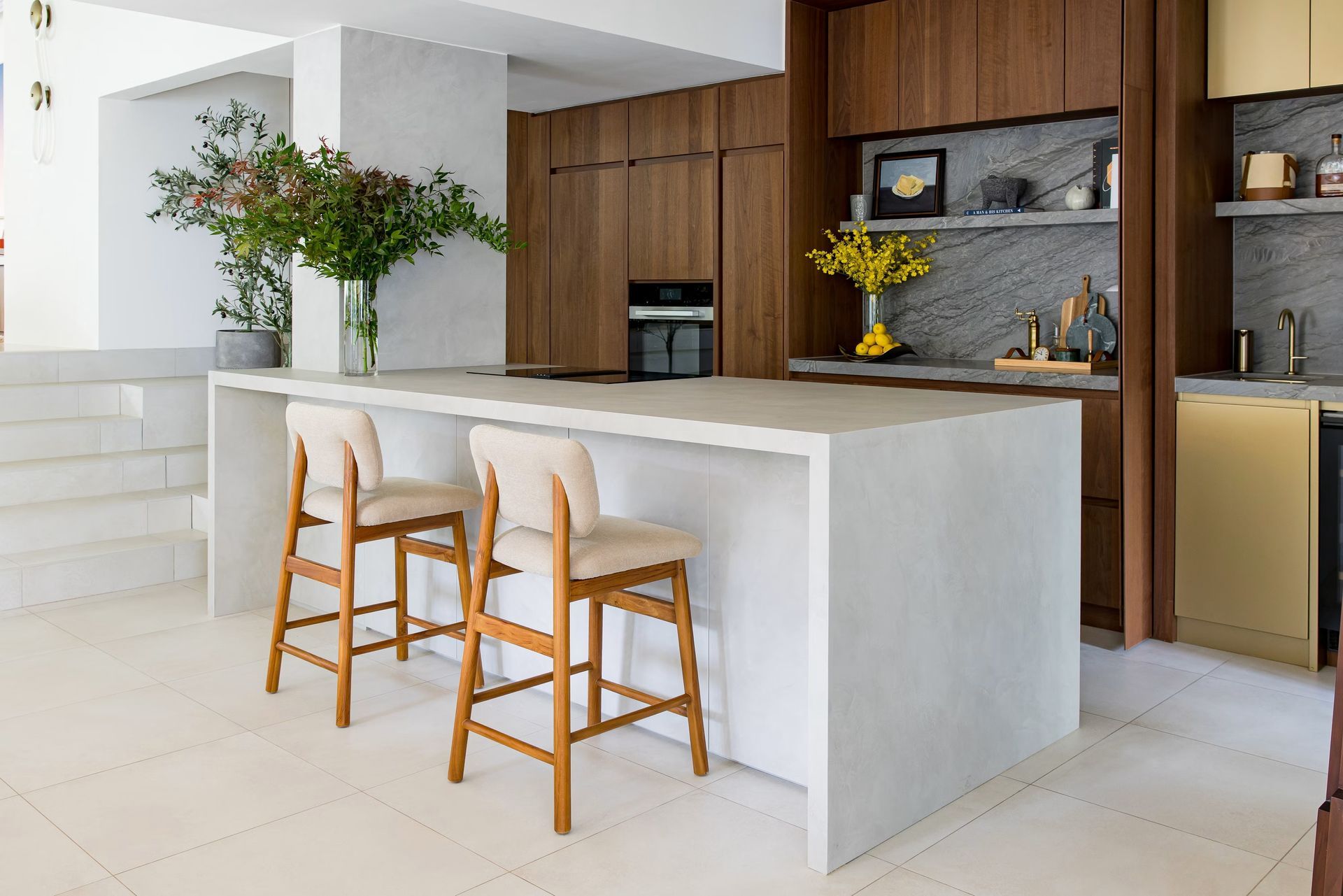 Modern kitchen with white island, wooden bar stools, and wood cabinetry