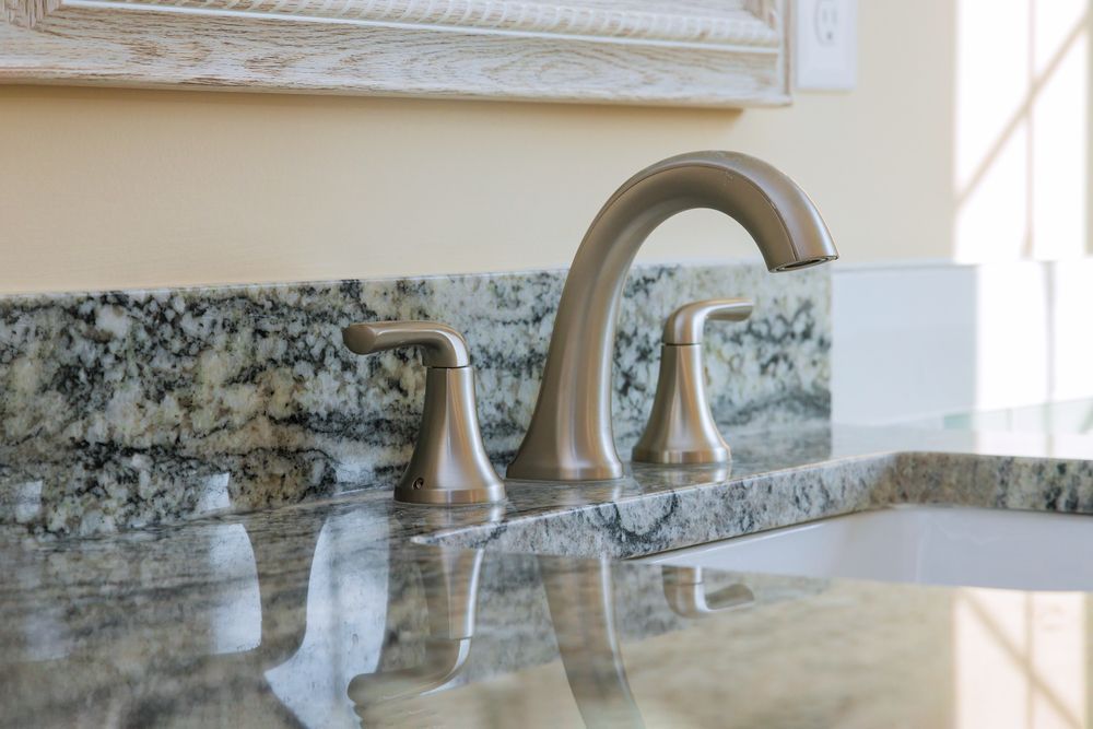 Granite bathroom sink with chrome faucet and matching handles on a polished countertop