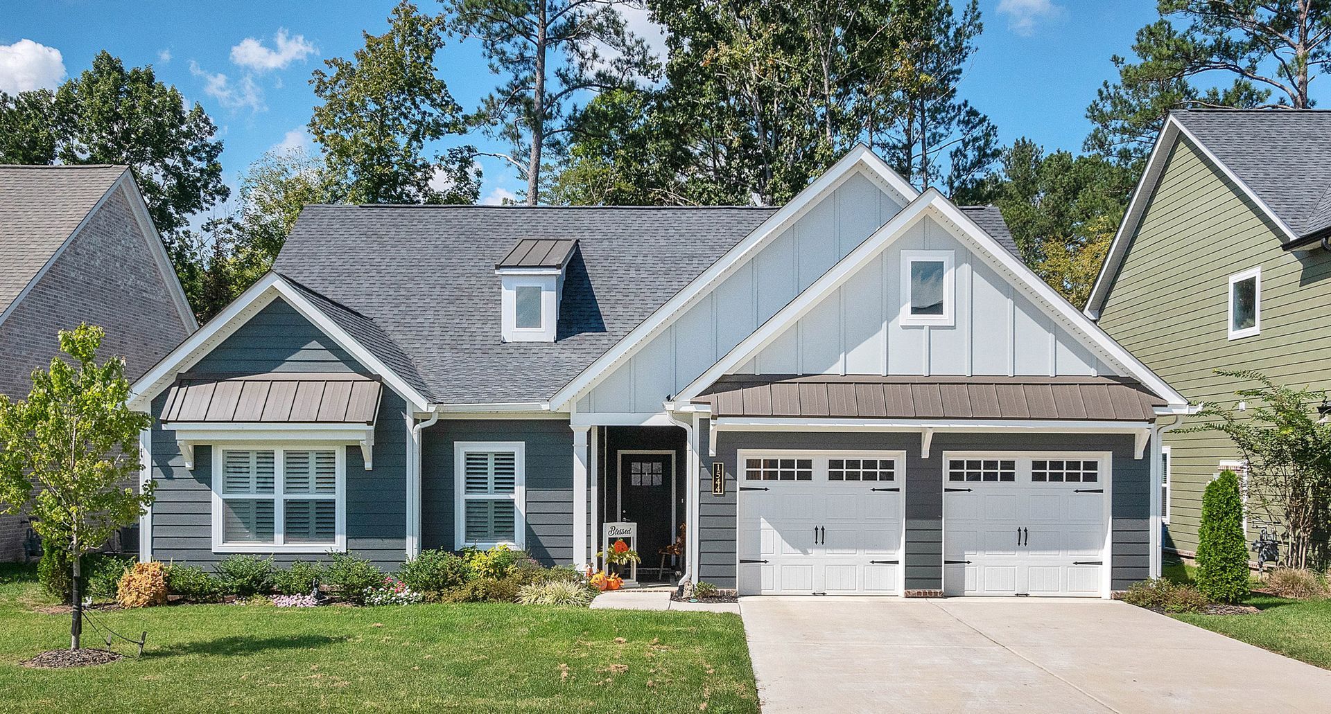 Single-story home with gray and white James Hardie siding, double garage doors, dormer windows, and landscaped front yard