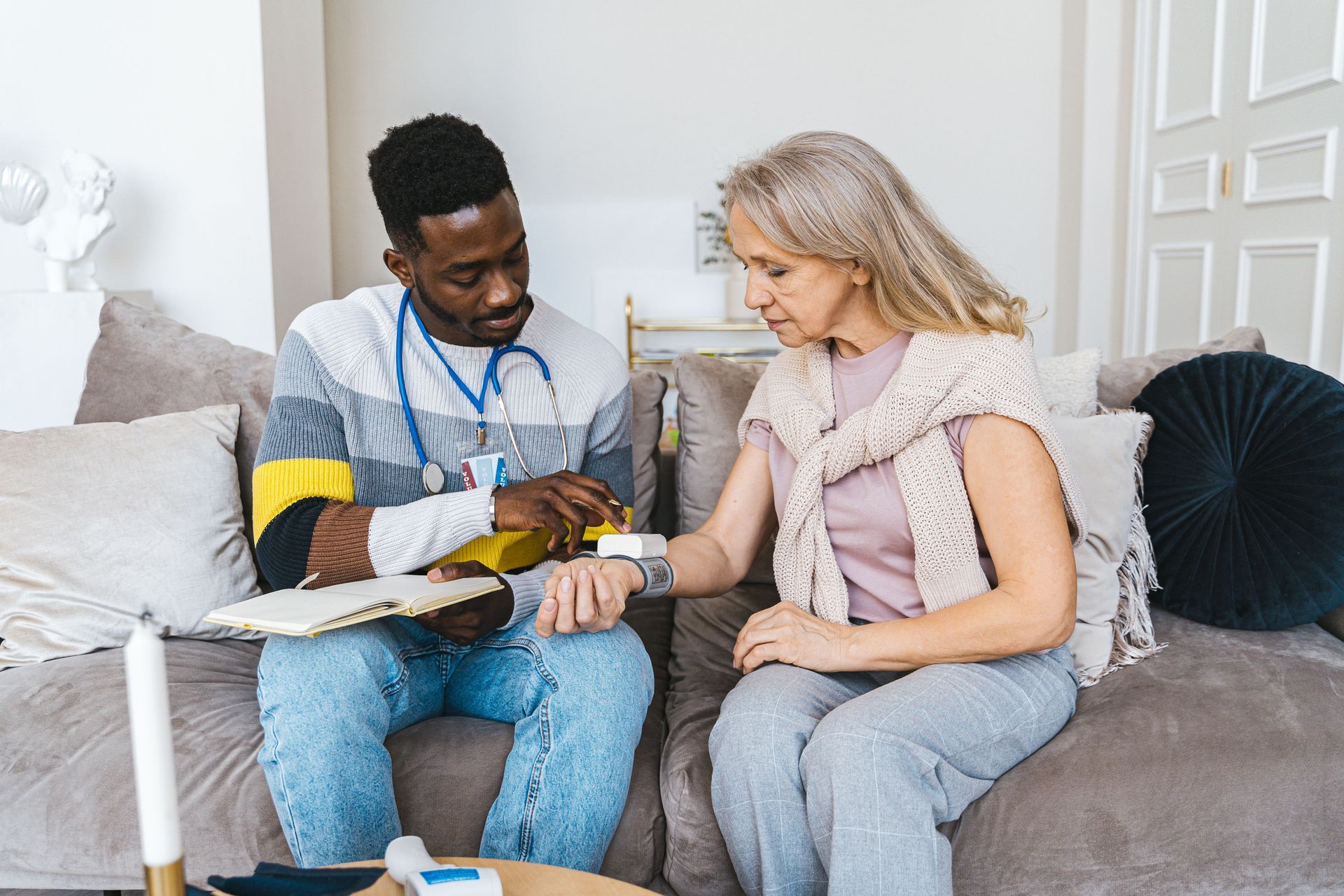 A nurse checks an older woman’s blood pressure at home