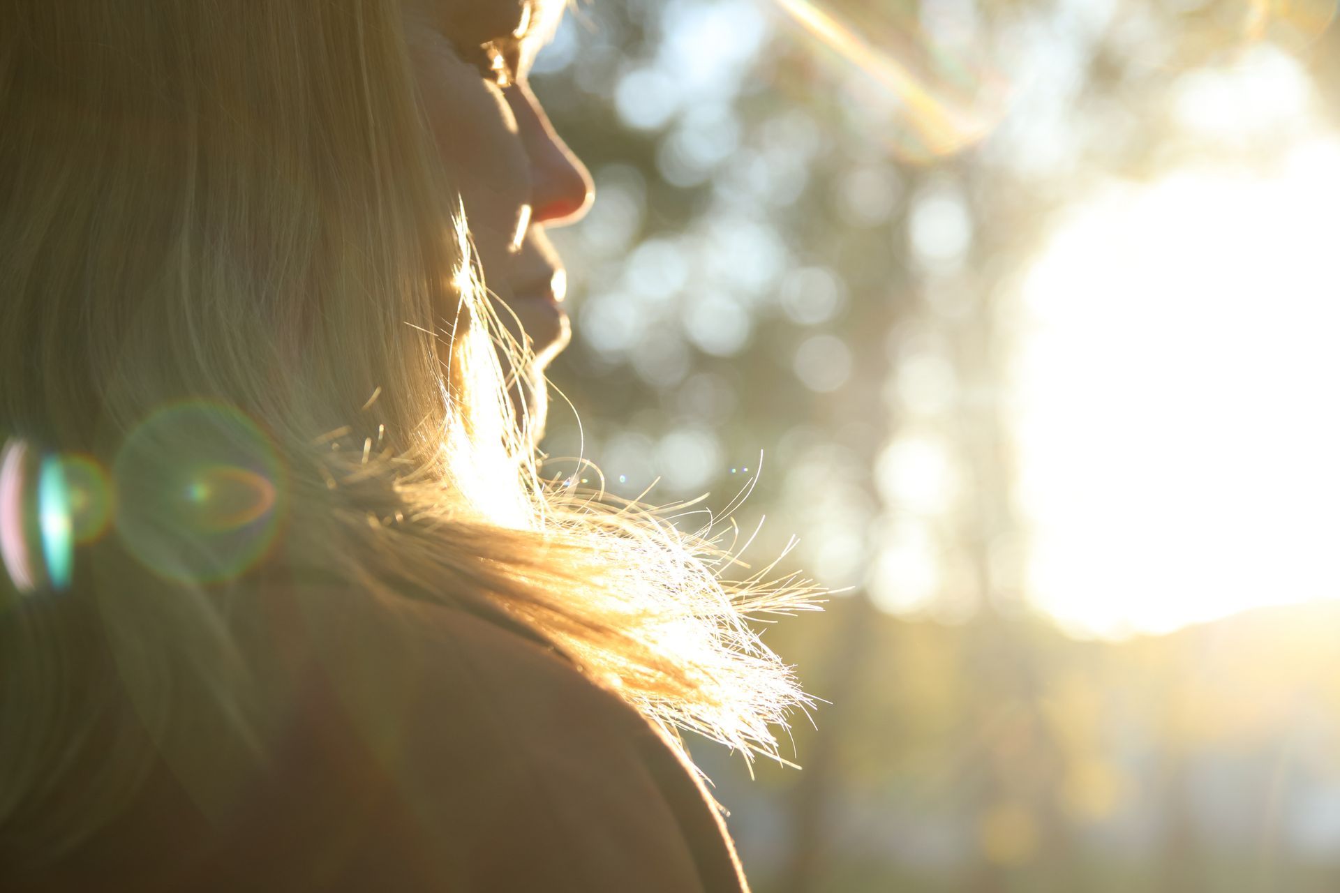 Backlit person in profile with sunlight and lens flare outdoors