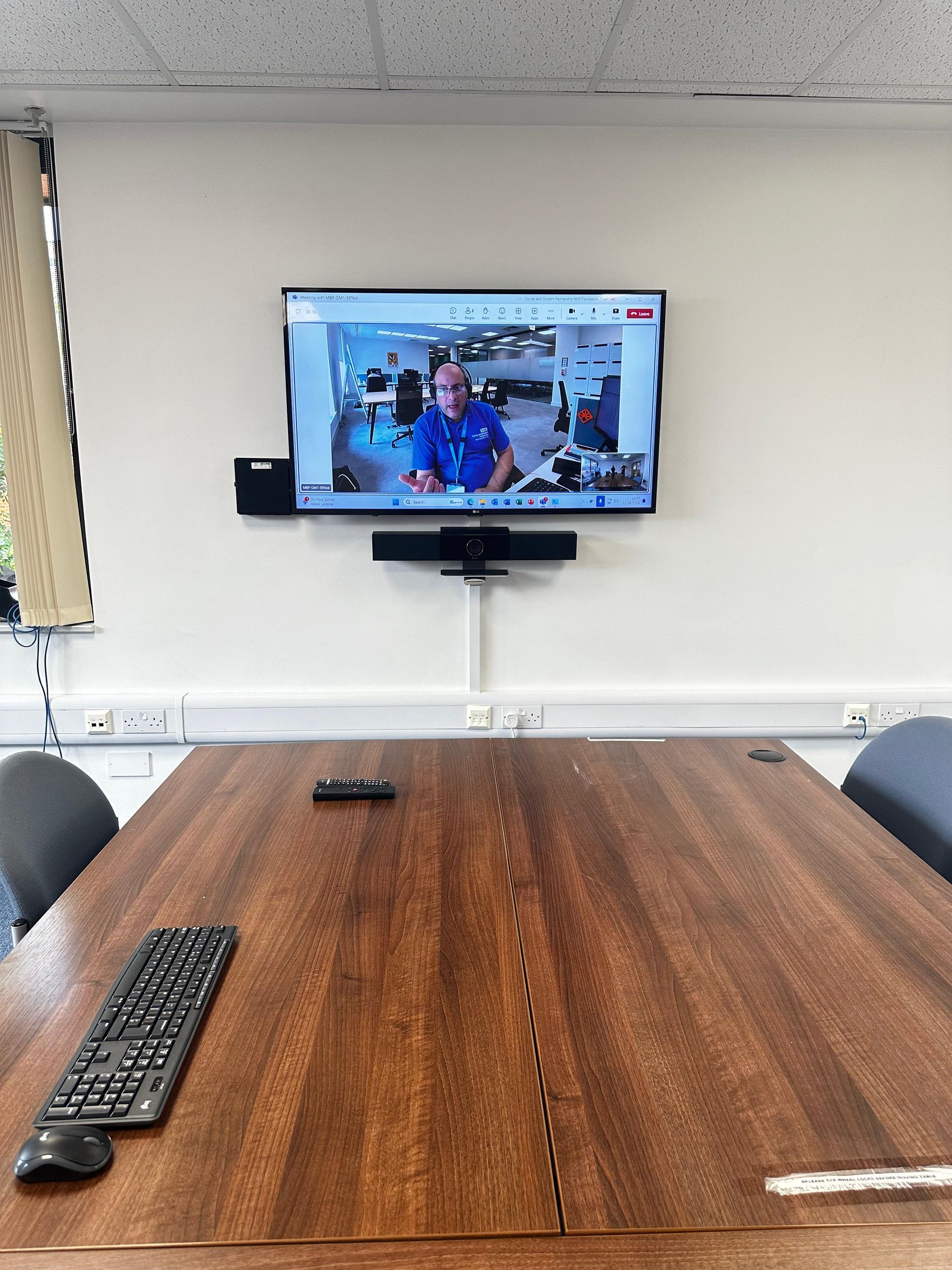 Meeting room with a wall-mounted video conferencing display and conference table