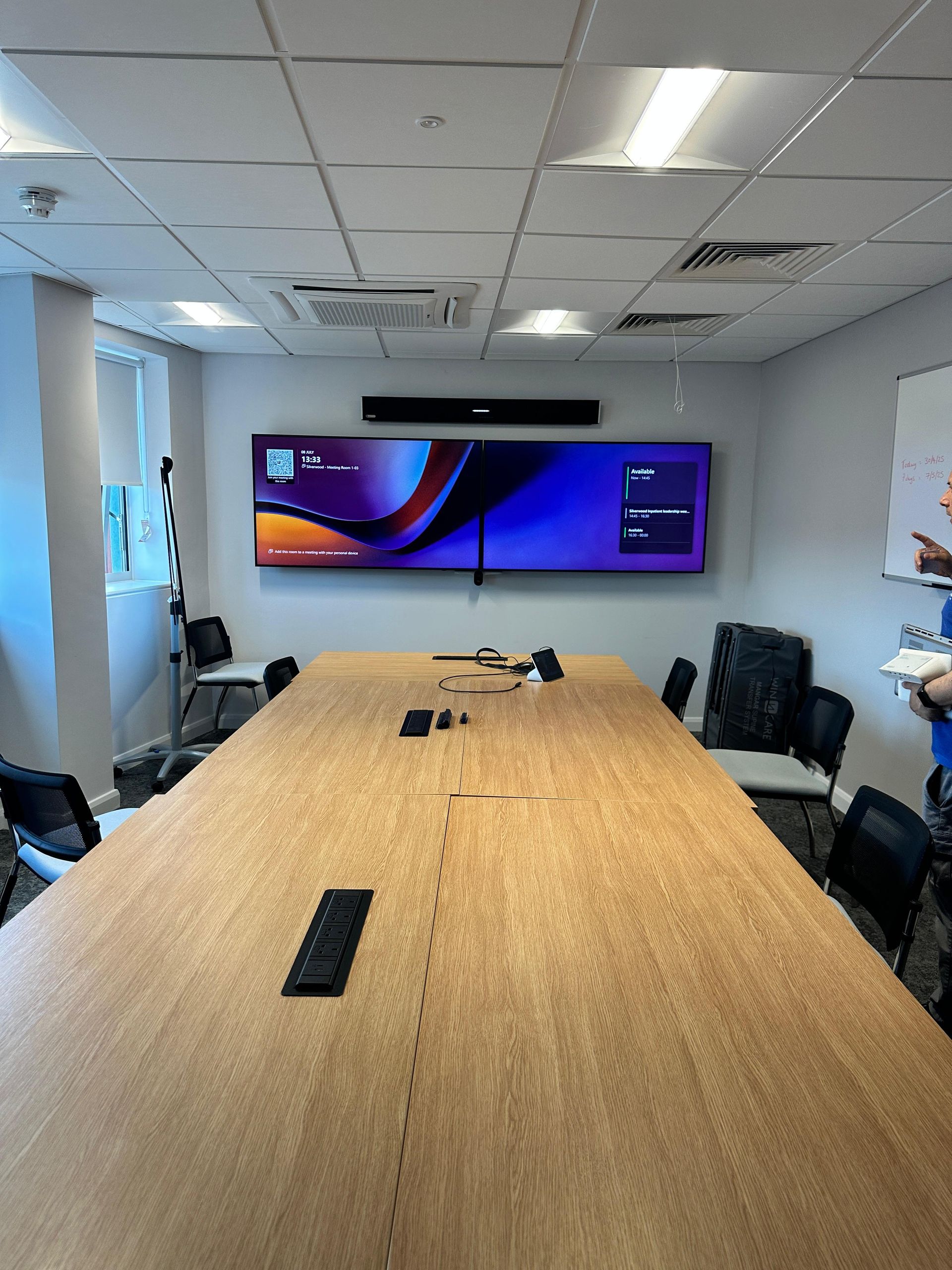 Large meeting room with dual video conferencing displays and a conference table