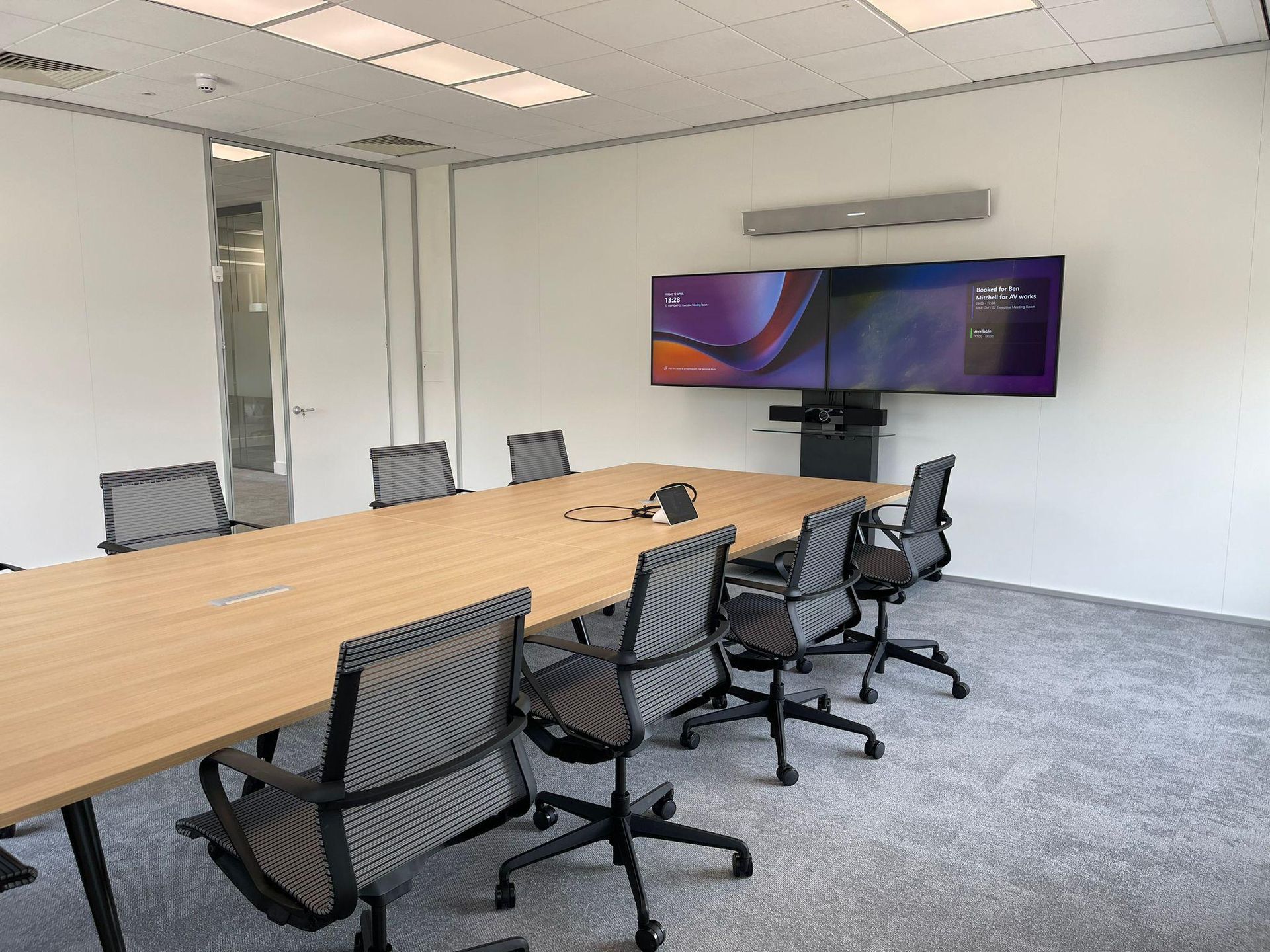 Boardroom with a wall-mounted video conferencing display and long conference table
