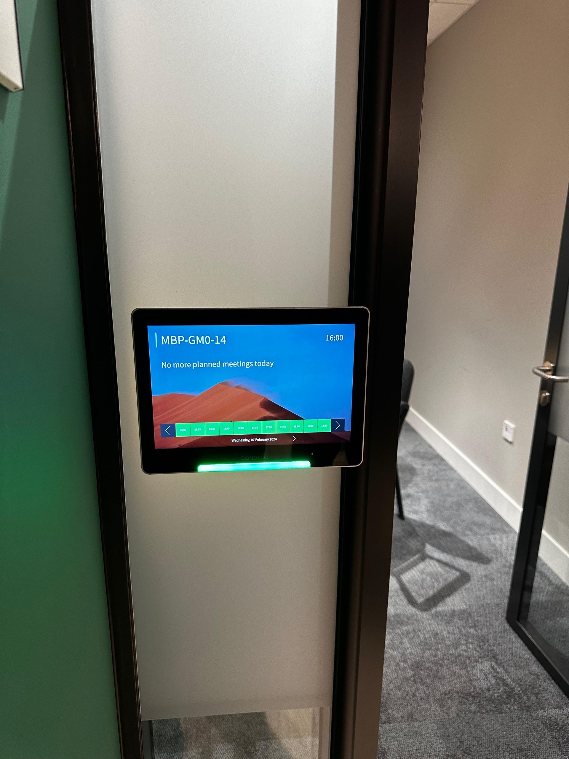 Close-up of a wall-mounted room booking panel outside a meeting room