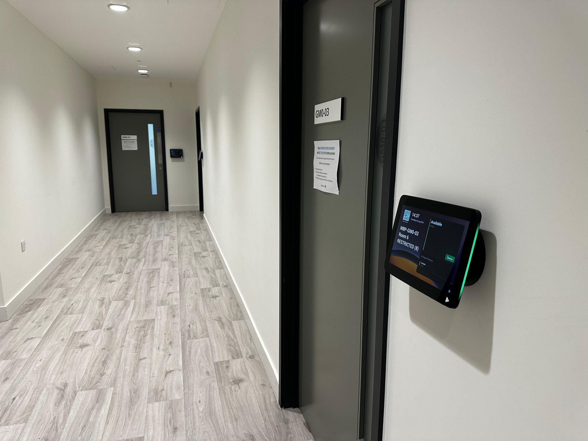 Office corridor with a room booking panel installed outside a meeting room
