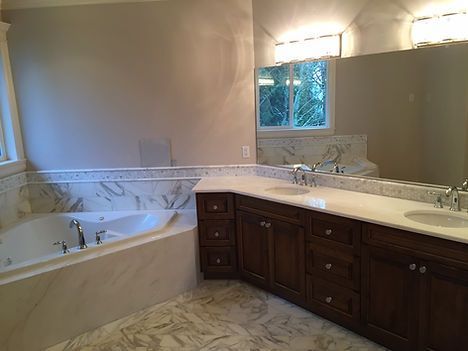 A bathroom with two sinks , a tub , and a large mirror.