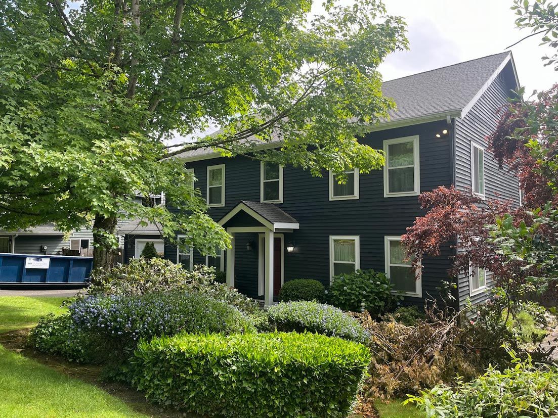 A large black house with a dumpster in front of it.