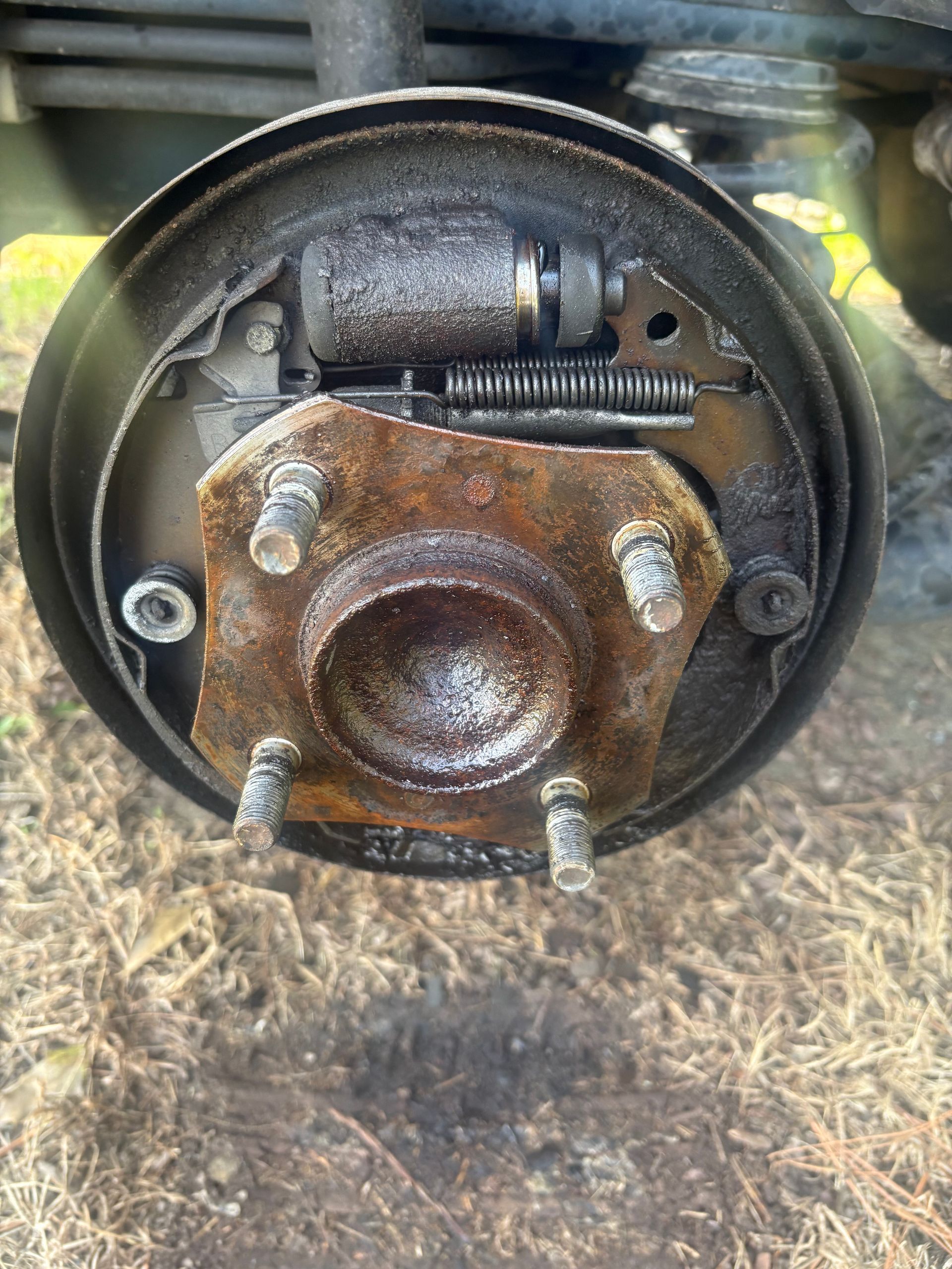 Rusty car brake drum and wheel hub close-up with exposed springs and bolts