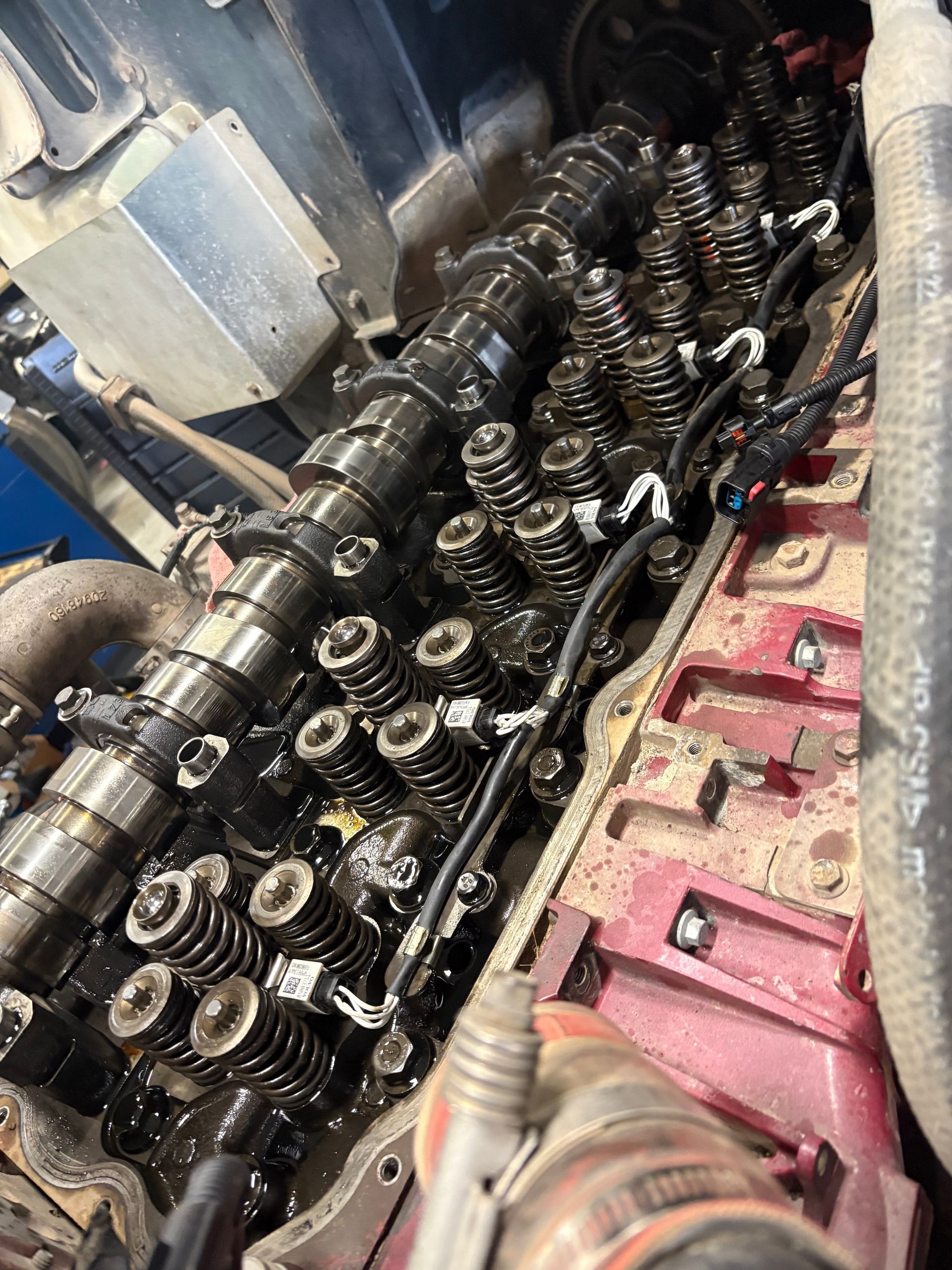 Close-up of a dirty engine cylinder head with exposed valve springs and camshaft components.