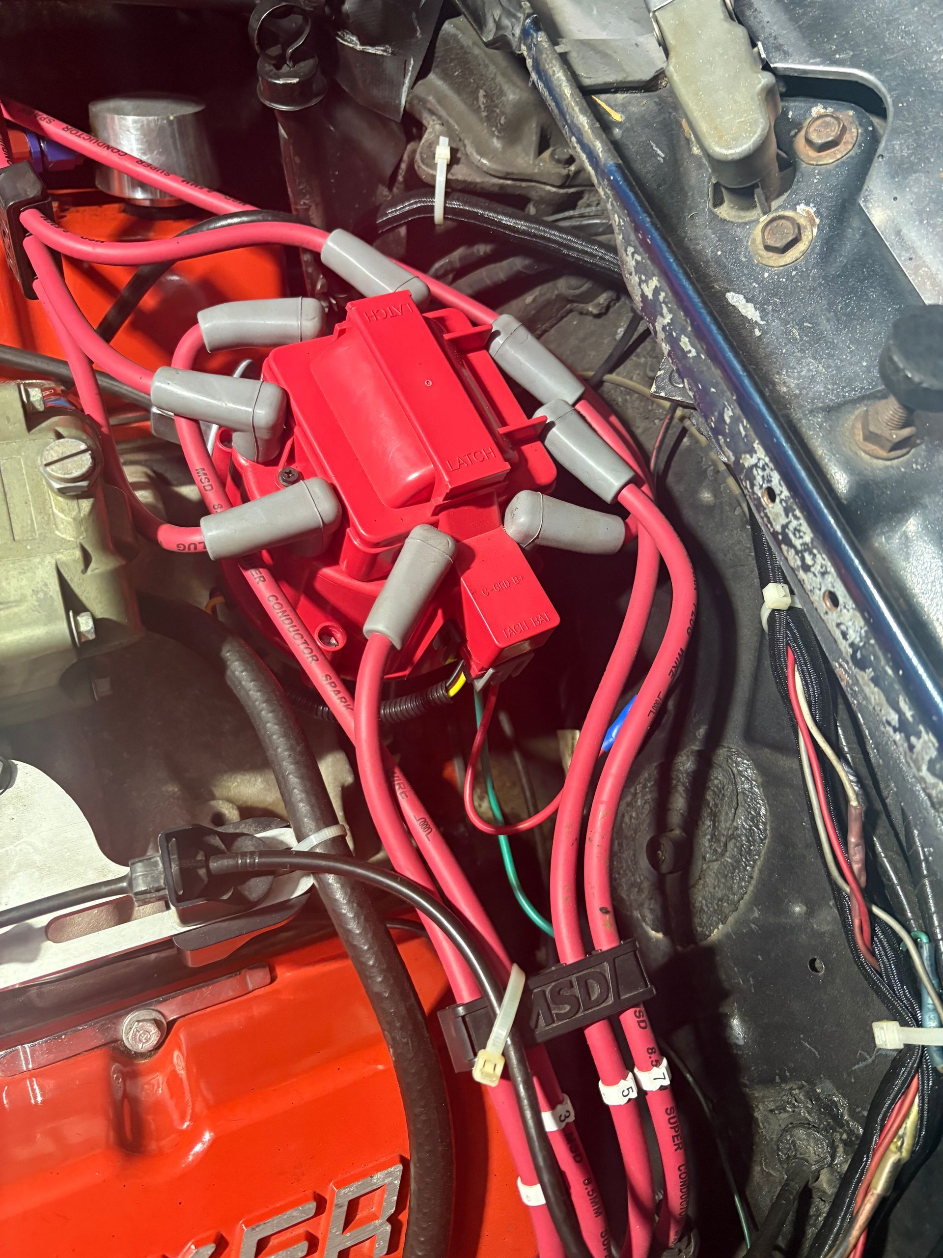 Red ignition coil and spark plug wires inside a car engine bay