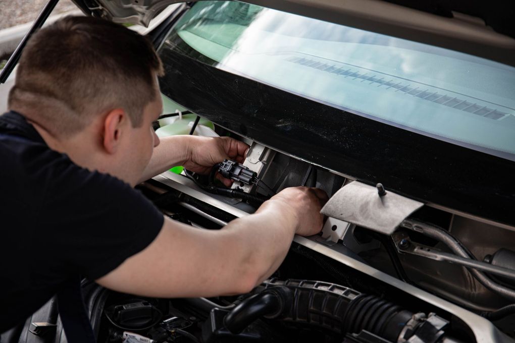 Person working under a car dashboard with tools in a garage