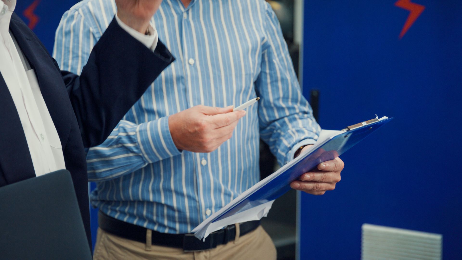 un uomo in camicia a righe tiene in mano una clipboard e una penna