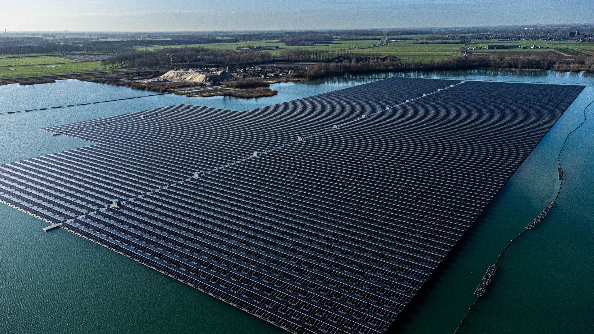 Een luchtfoto van een groot drijvend zonnepark midden op een meer.