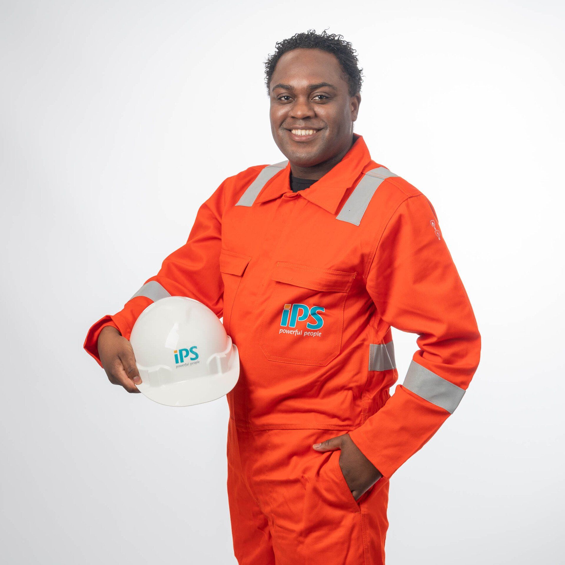 Een man in een oranje overall houdt een helm vast.