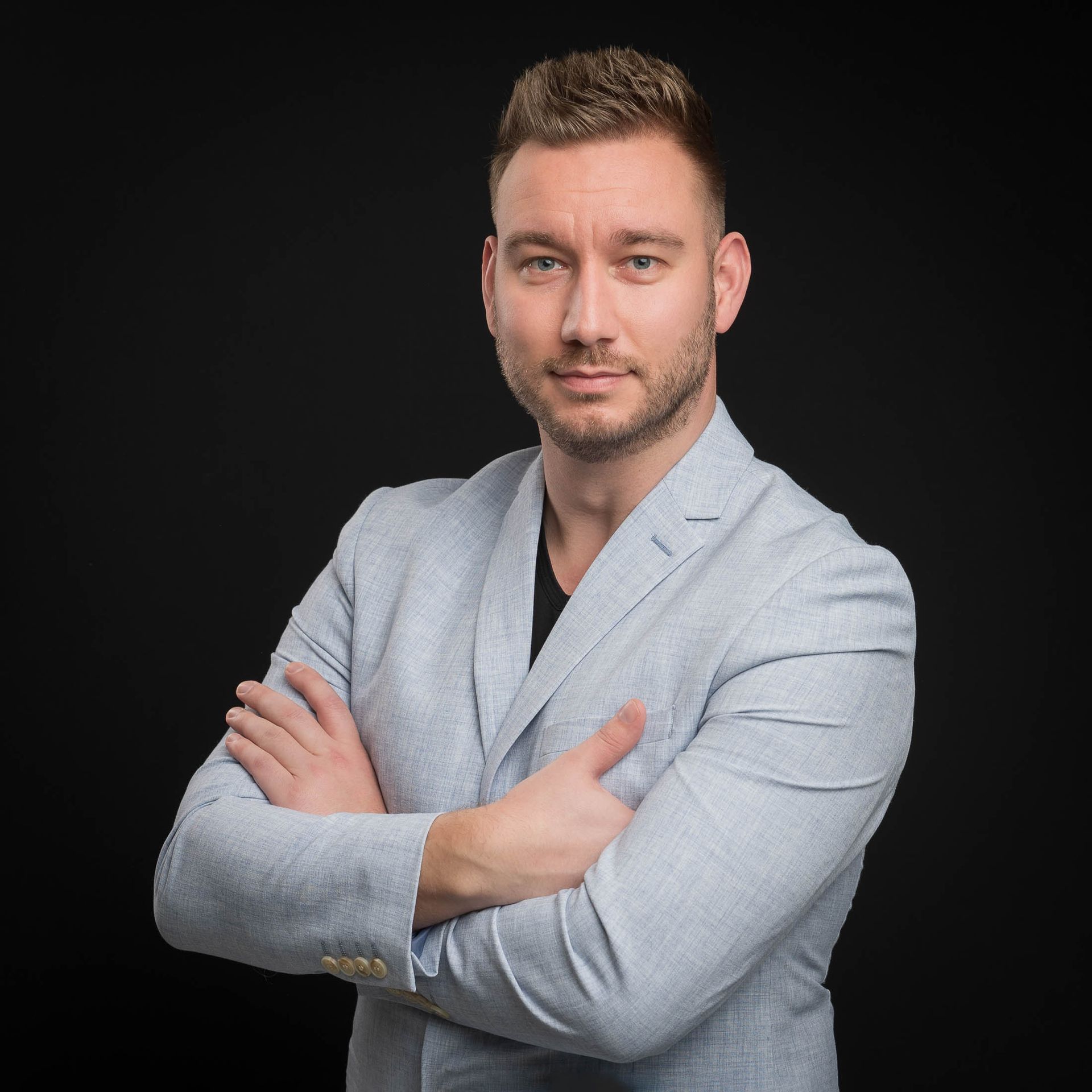 Een man in pak staat met zijn armen over elkaar.