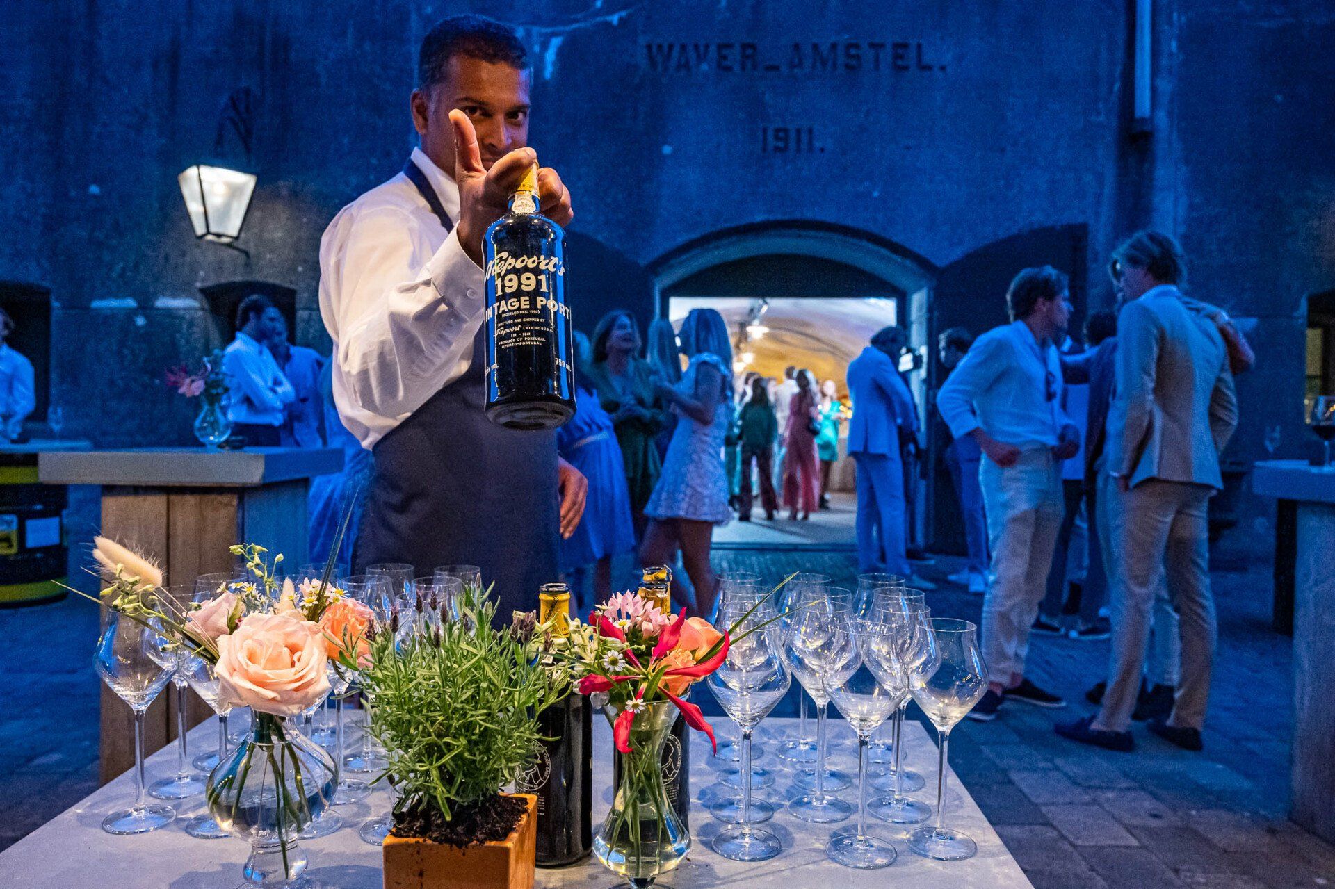 Een man schenkt op een feestje een drankje in een glas.