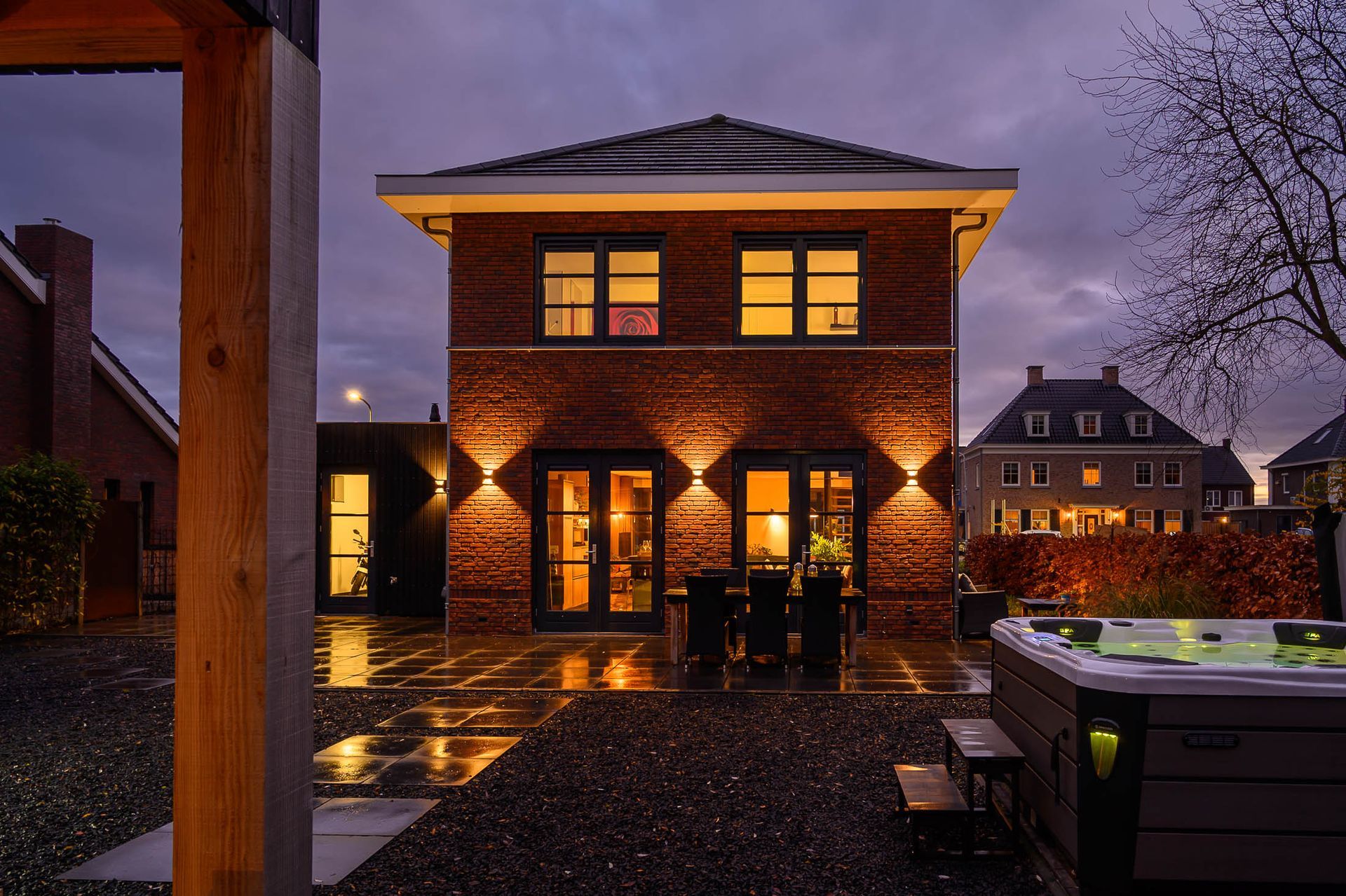 's Avonds staat er een groot, verlicht bakstenen huis met een hottub ervoor.