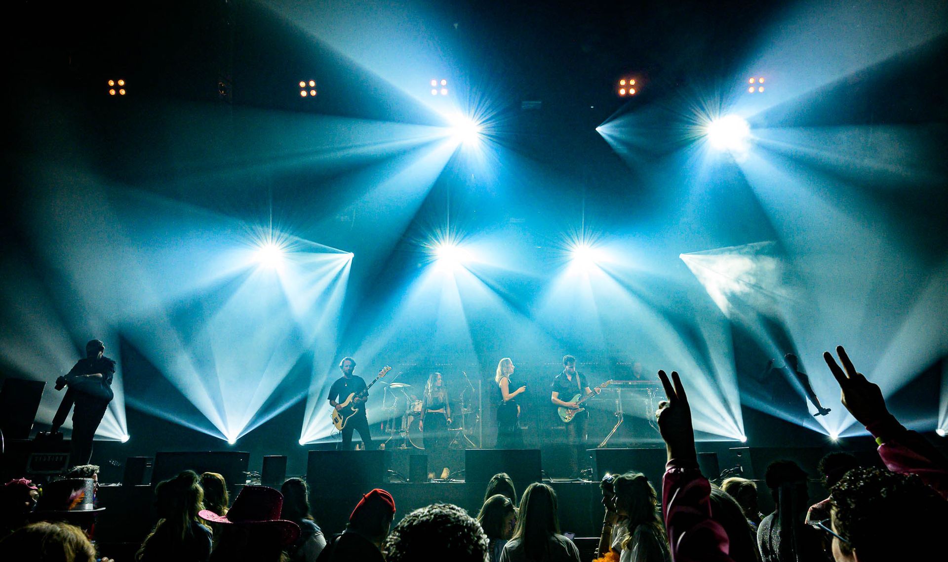 Een groep mensen kijkt naar een band op het podium tijdens een concert.