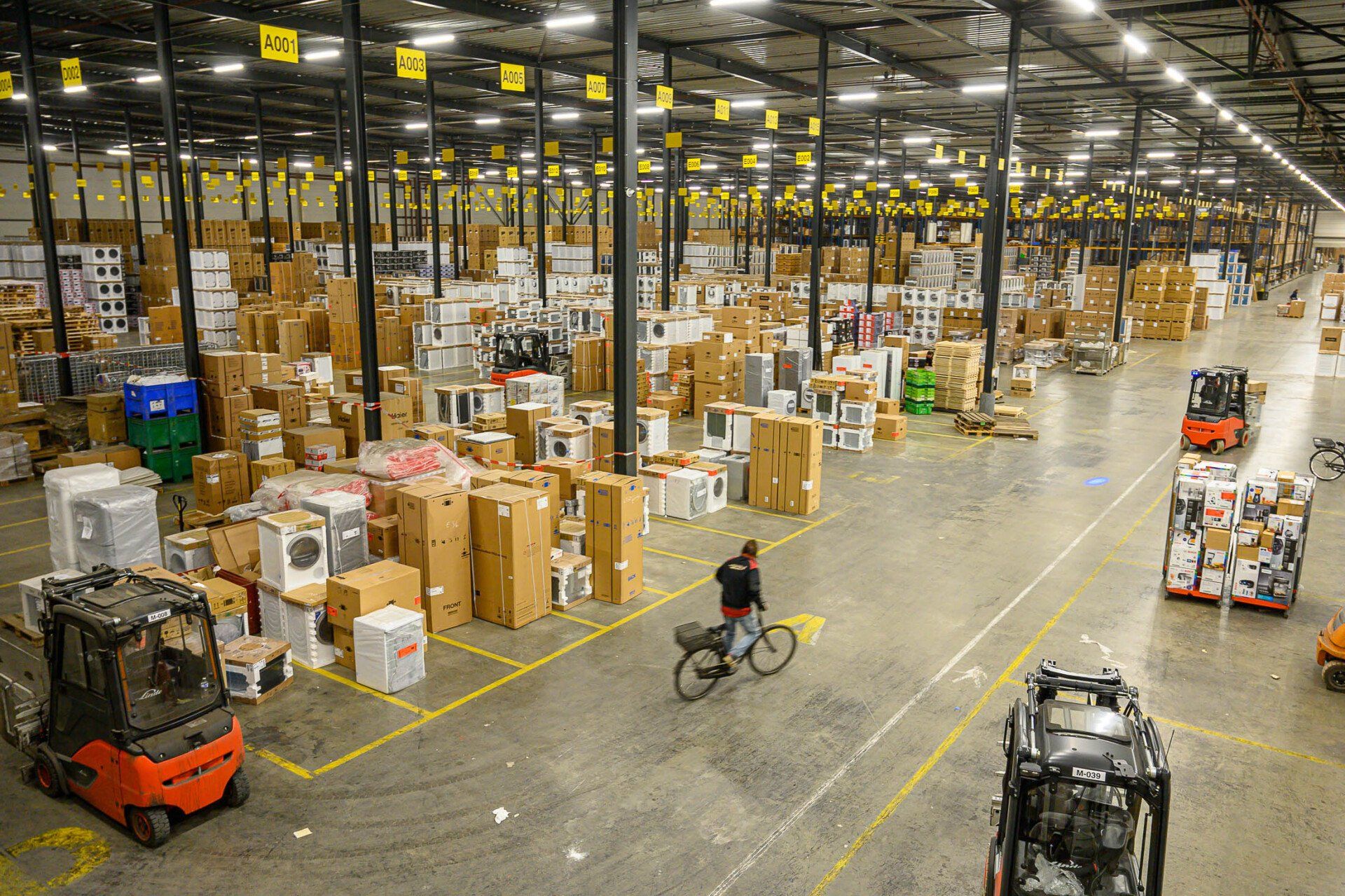 Een man fietst in een groot pakhuis.
