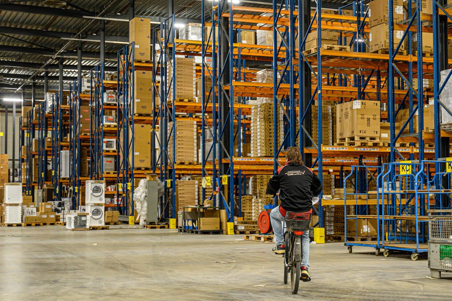 Een man fietst in een groot pakhuis.