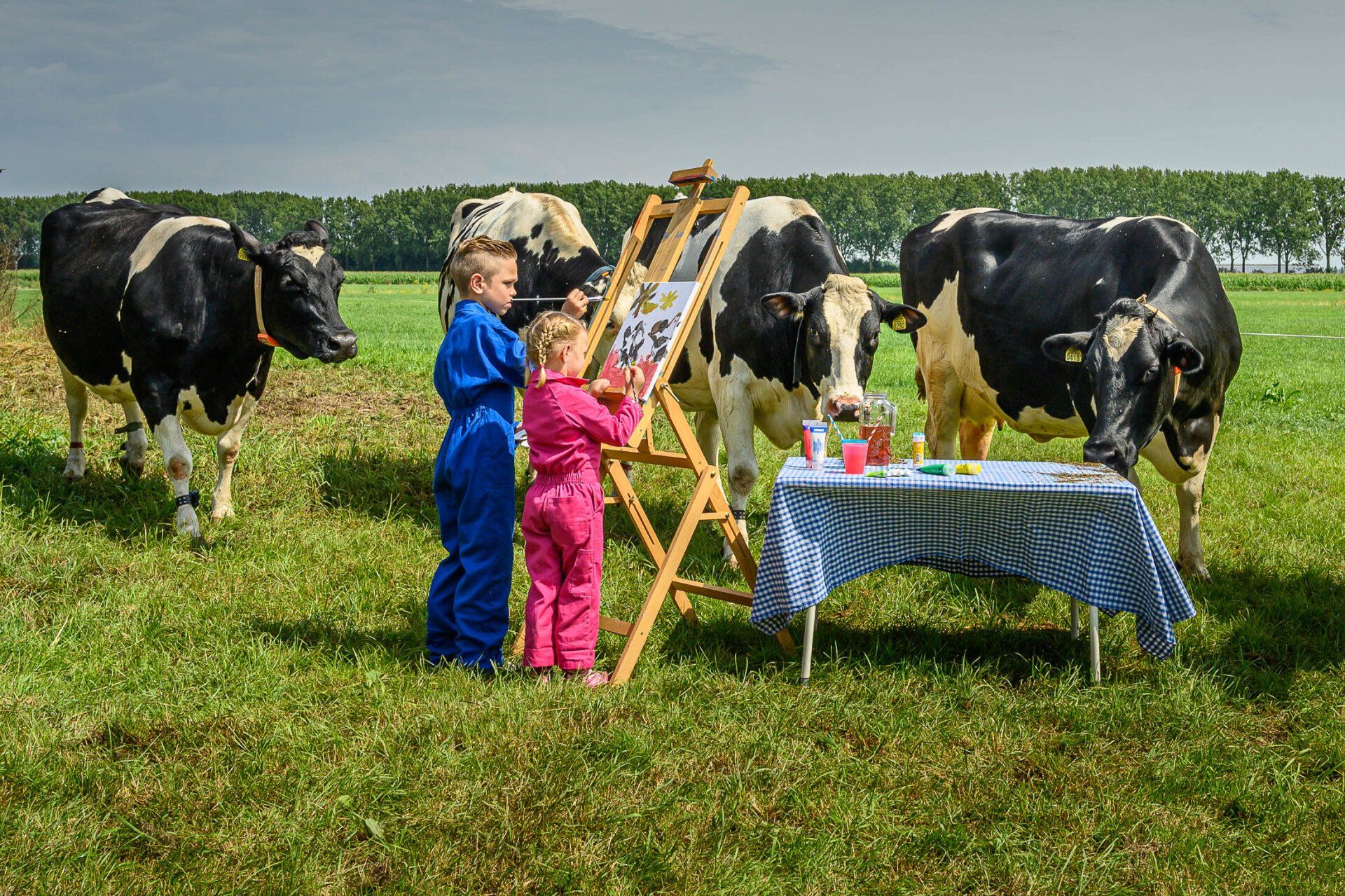 Een jongen en een meisje schilderen koeien in een veld.