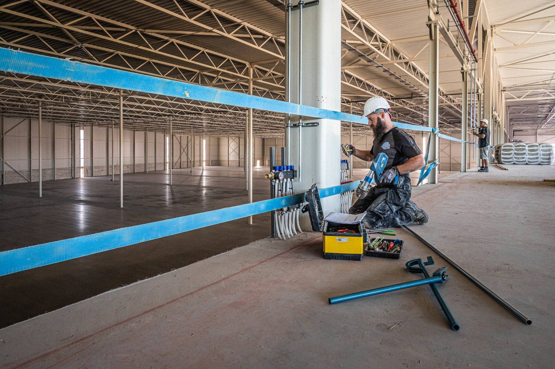 Een man knielt op de vloer van een gebouw in aanbouw.