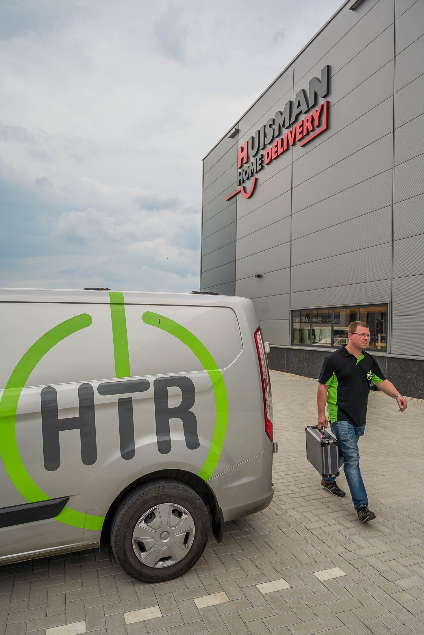 Een man loopt naar een busje waar htr op staat.
