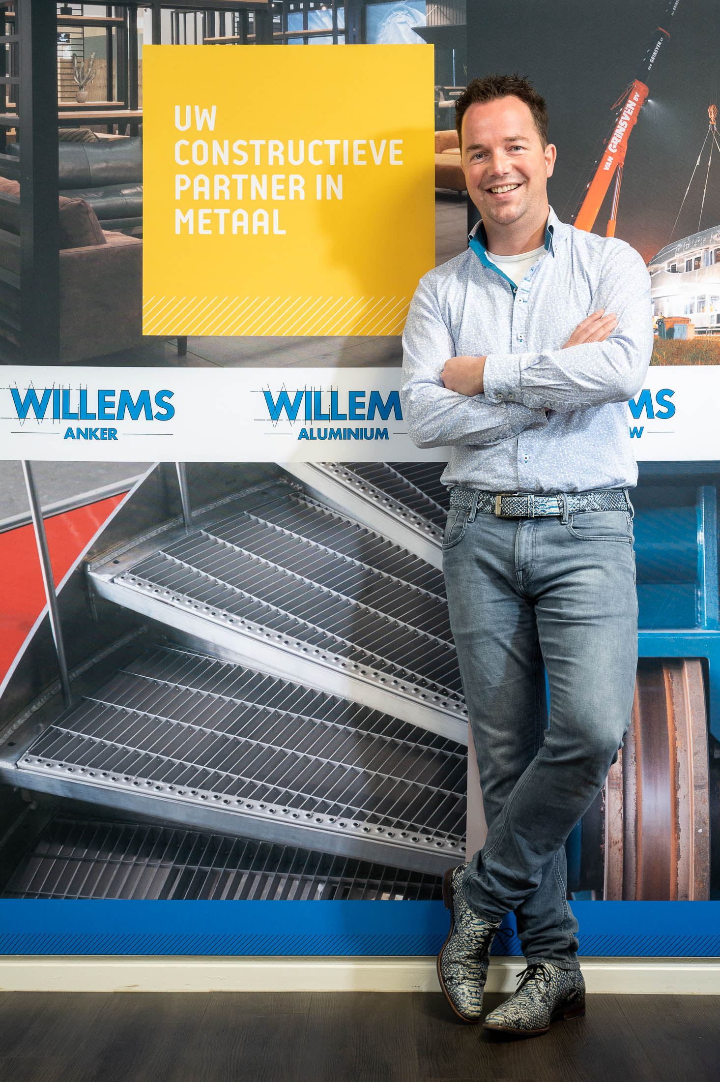 Een man staat voor een muur met zijn armen over elkaar.