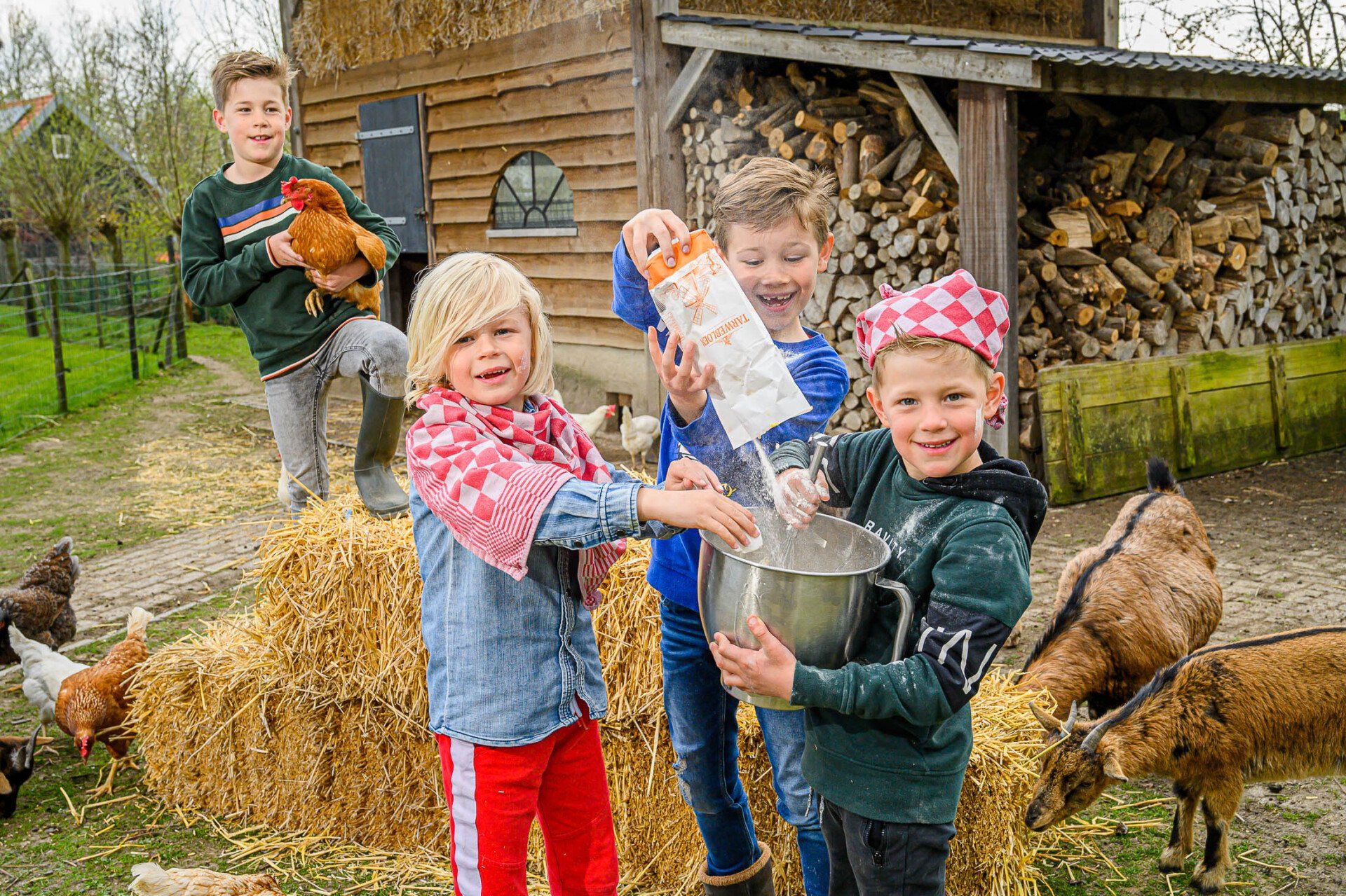 Een groepje kinderen staat naast een stapel hooi.