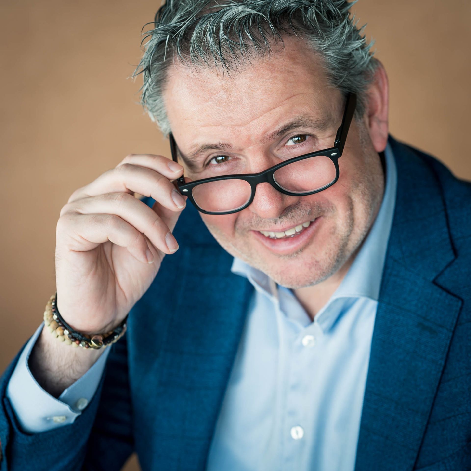 Een man met een bril en een blauw pak lacht