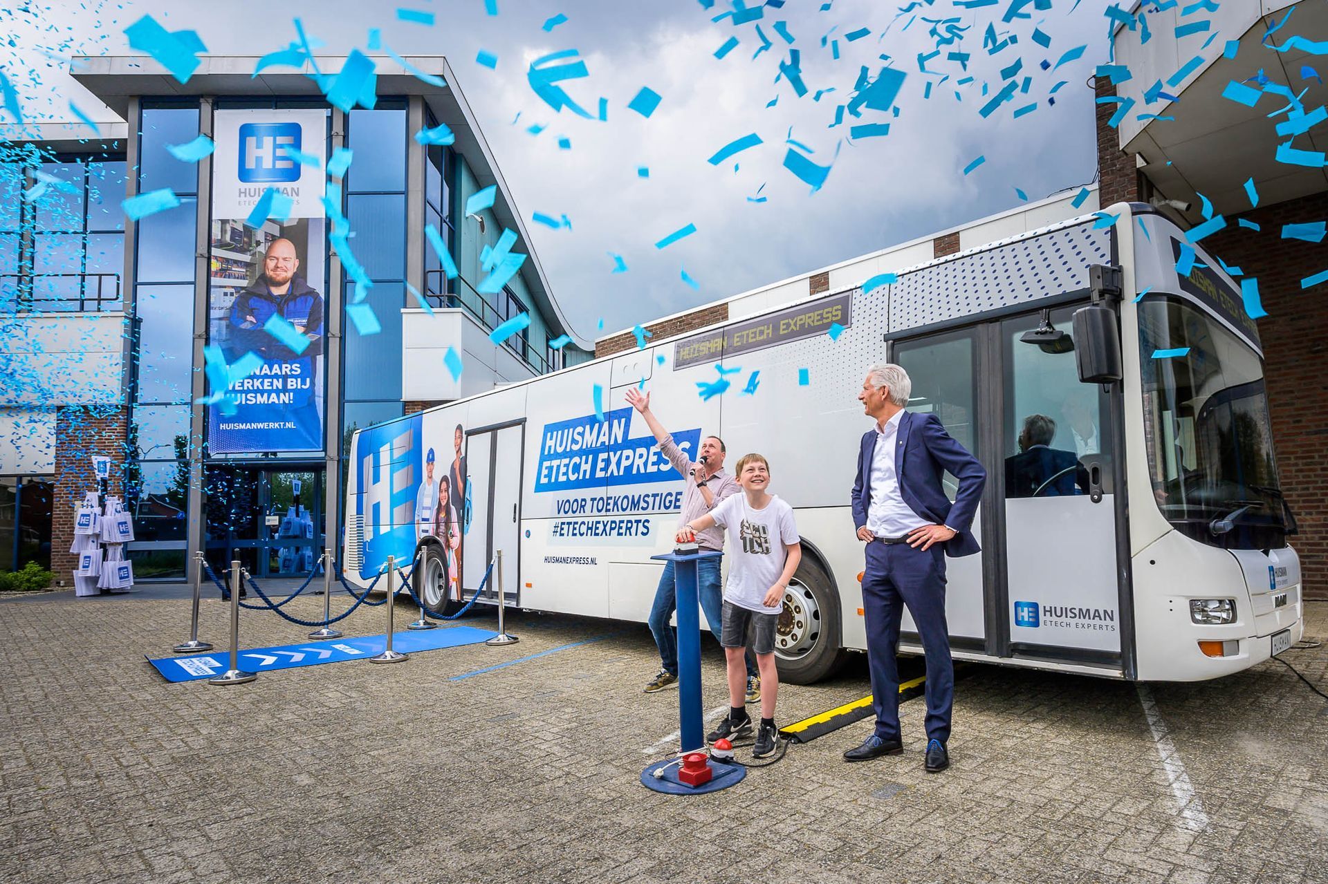 Een bus staat geparkeerd voor een gebouw terwijl er confetti uit de lucht valt.