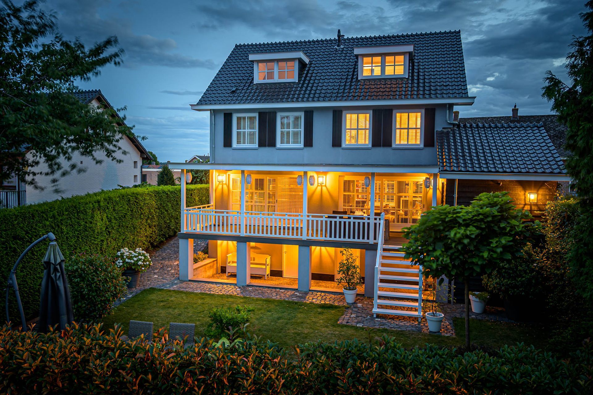 Een groot huis met veel ramen is 's nachts verlicht.