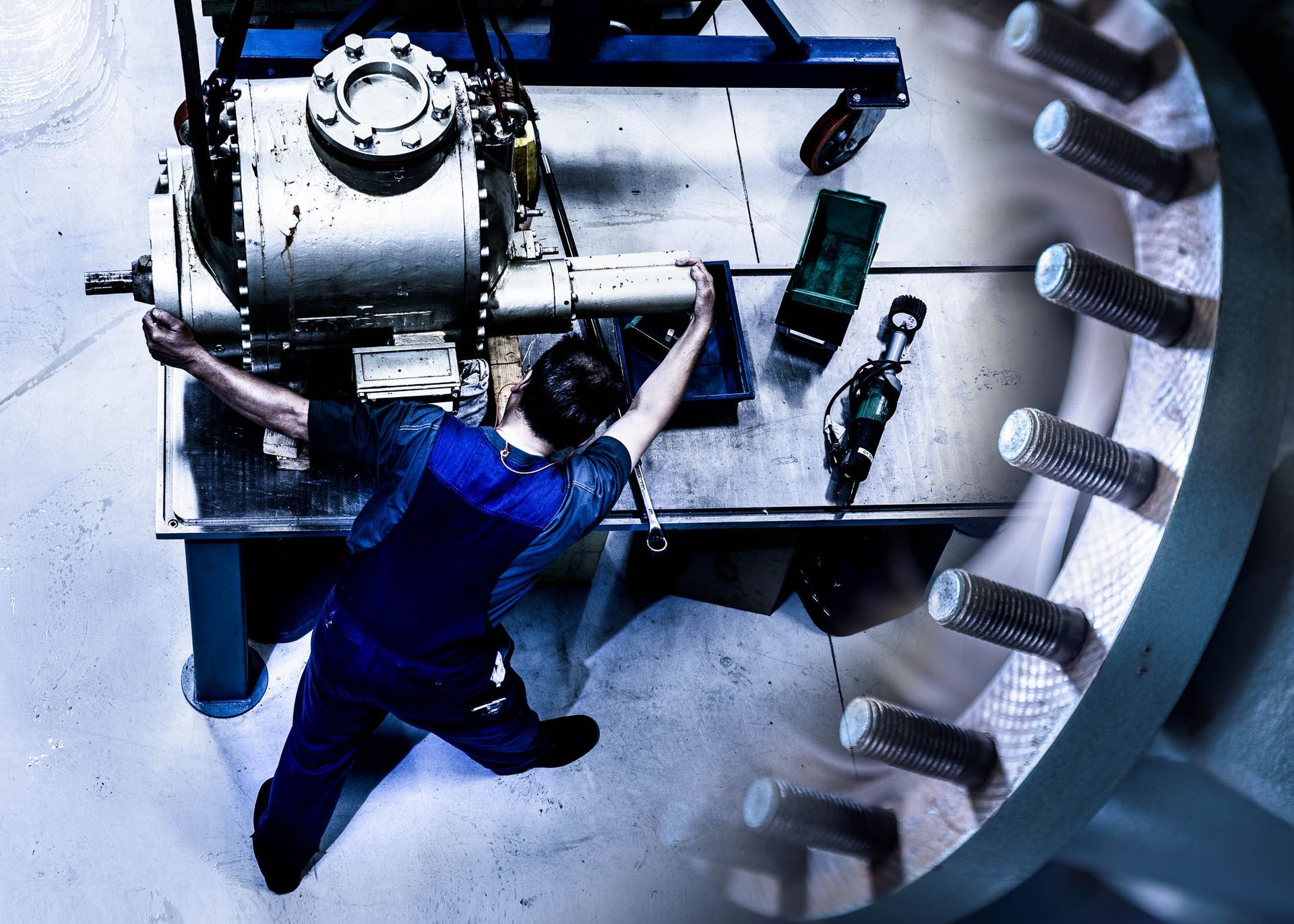Een man in een blauwe overall werkt aan een machine