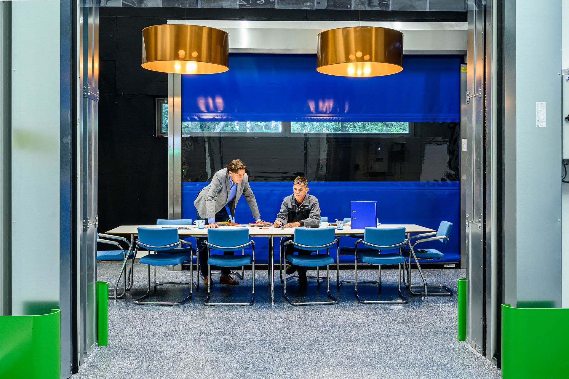 Twee mensen zitten aan een tafel in een vergaderruimte.