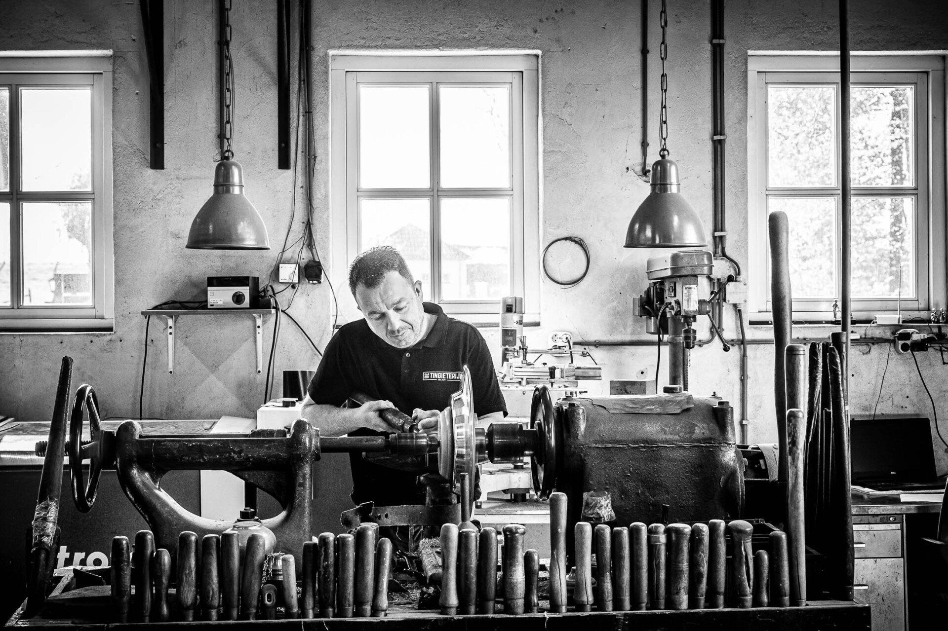 Op een zwart-witfoto is een man te zien die aan een machine werkt.