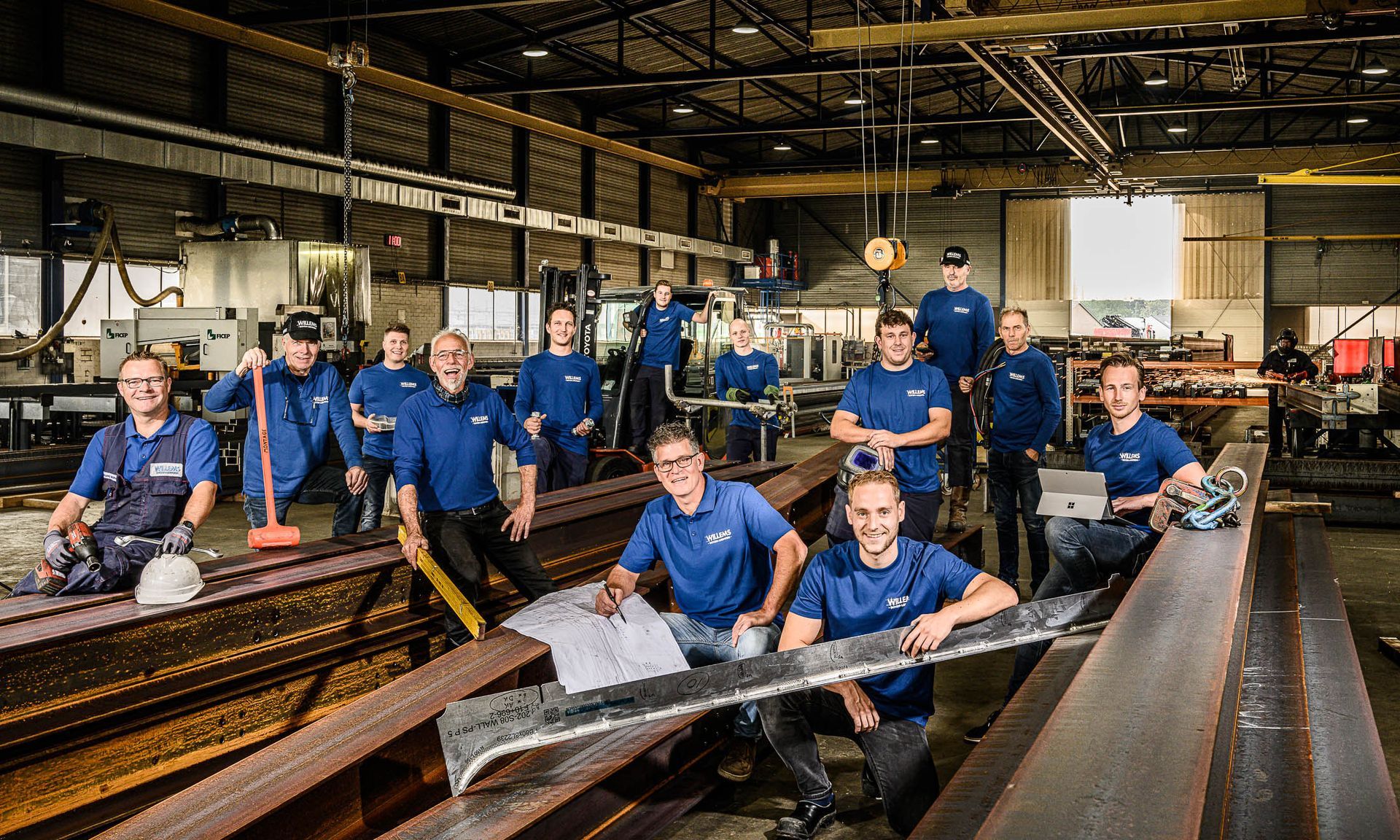 Een groep mannen poseert voor een foto in een fabriek.