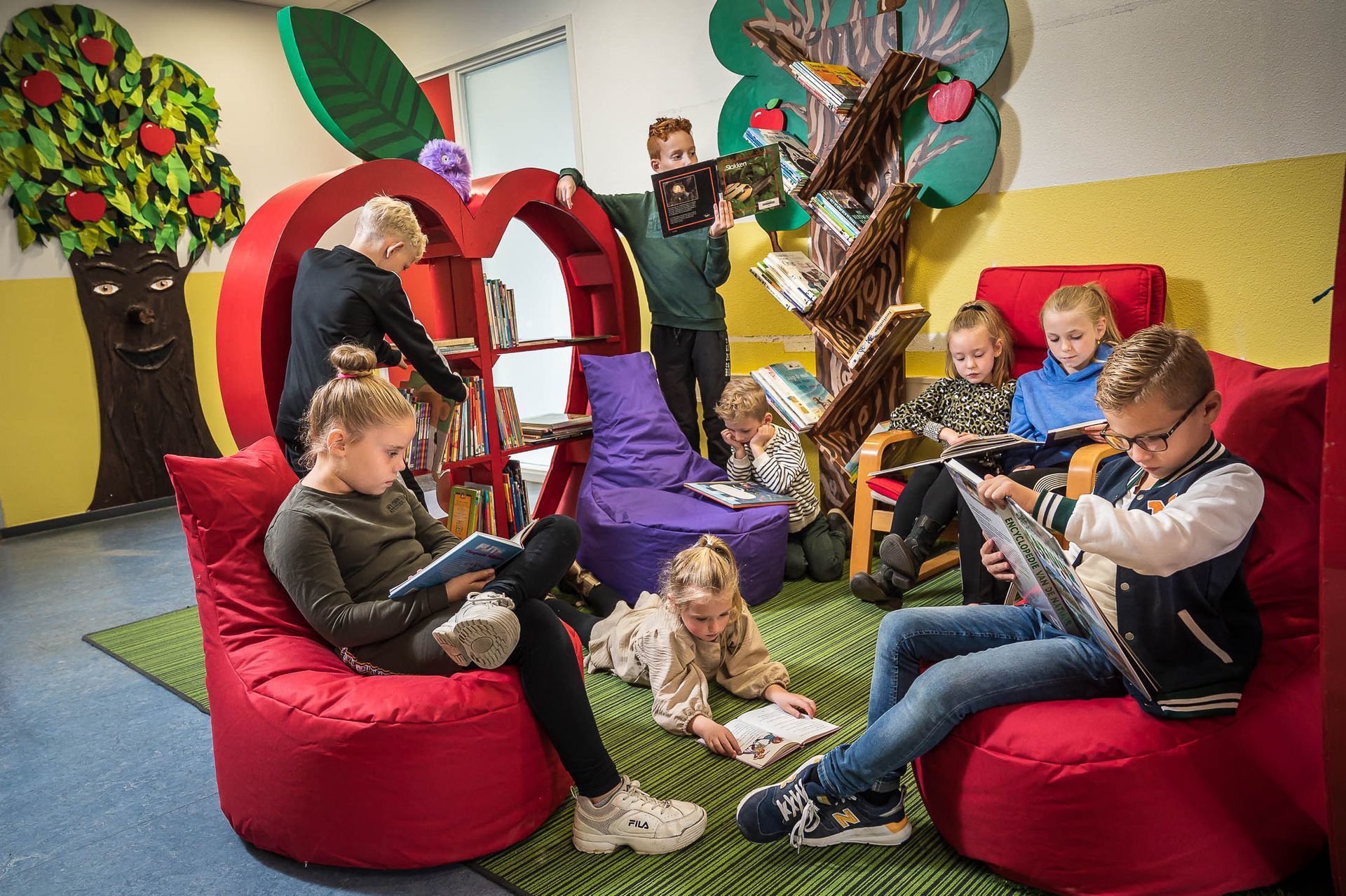 Een groep kinderen leest boeken in een bibliotheek.