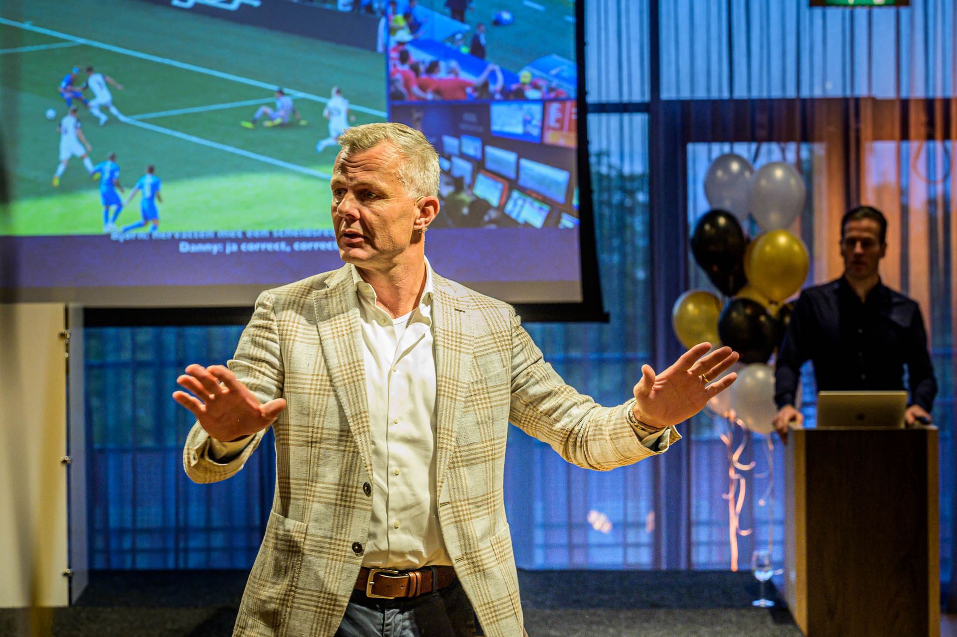 Een man geeft een presentatie voor een groot scherm.