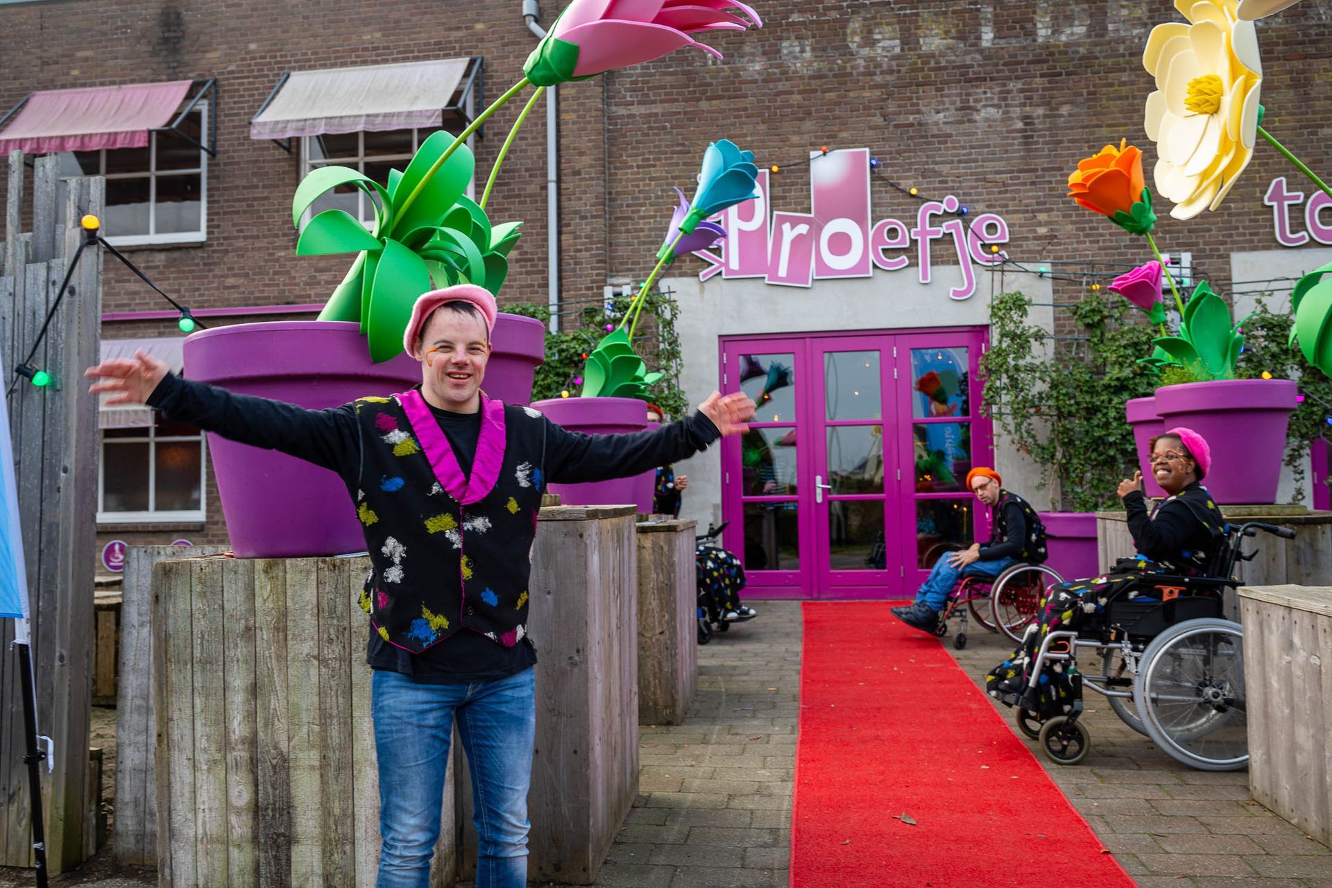 Een vrouw in een rolstoel staat op een rode loper voor een gebouw.