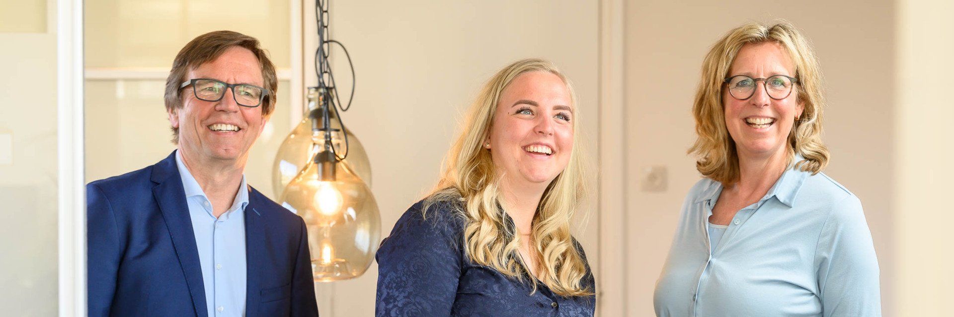 Een man en twee vrouwen staan naast elkaar en lachen.
