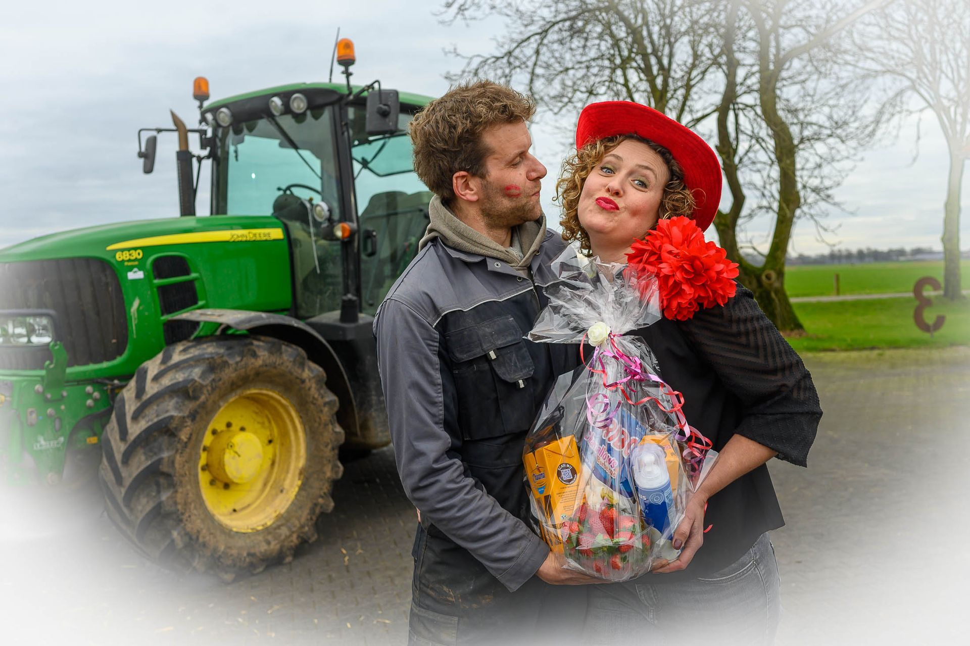 Een man en een vrouw staan voor een groene John Deere tractor.