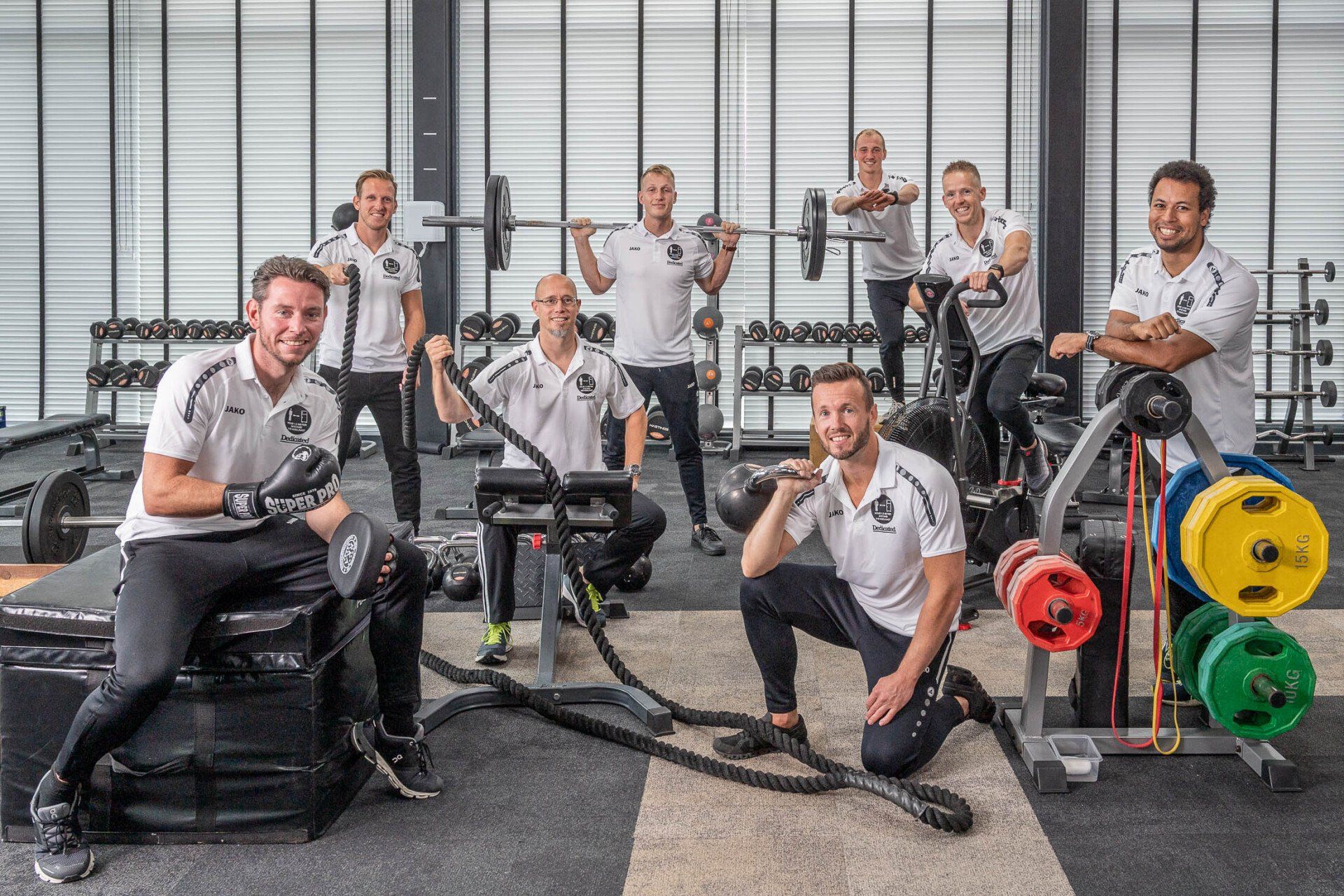 Een groep mannen poseert voor een foto in een sportschool.