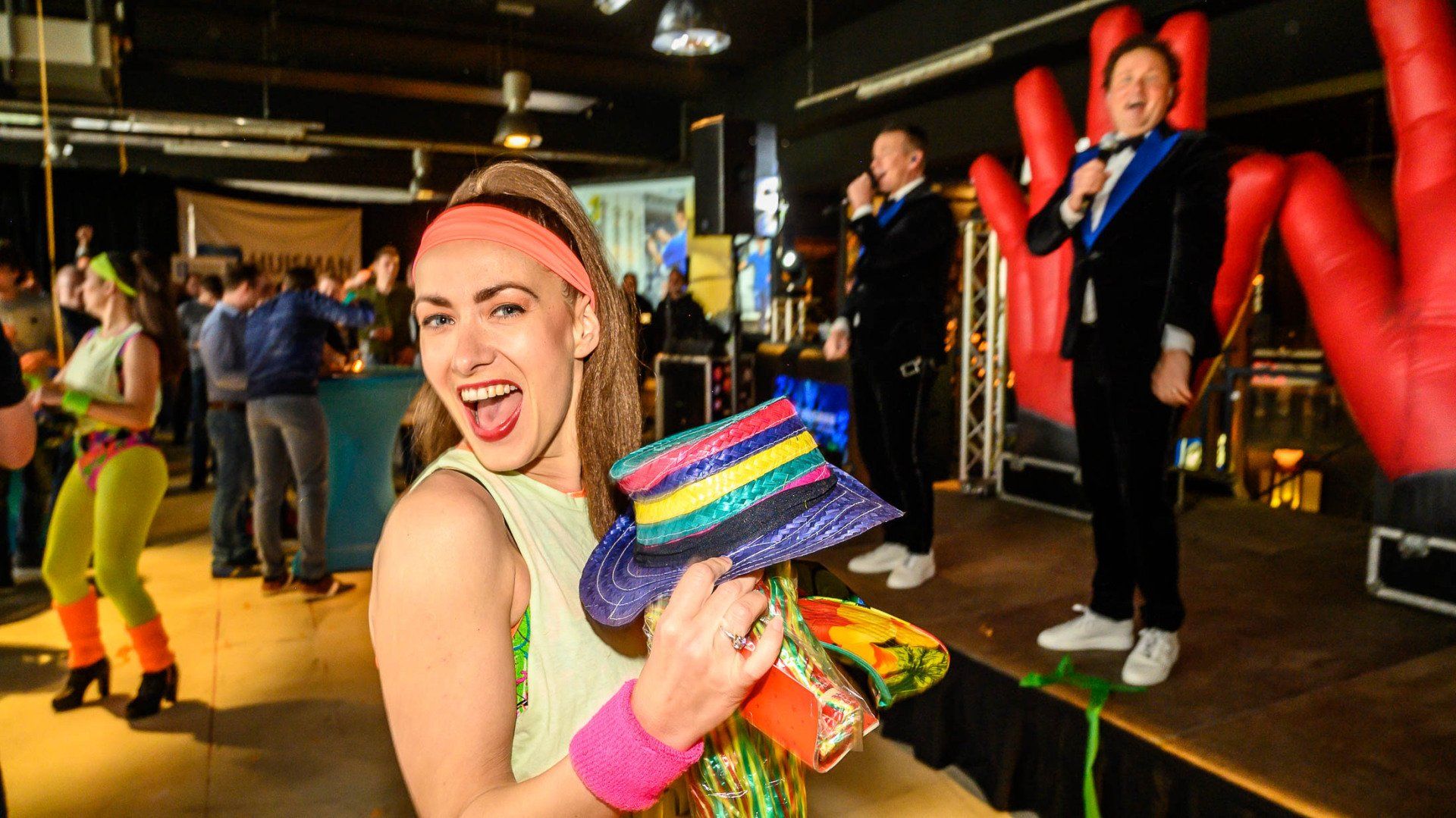 Een vrouw staat op een podium met een hoed in haar hand.
