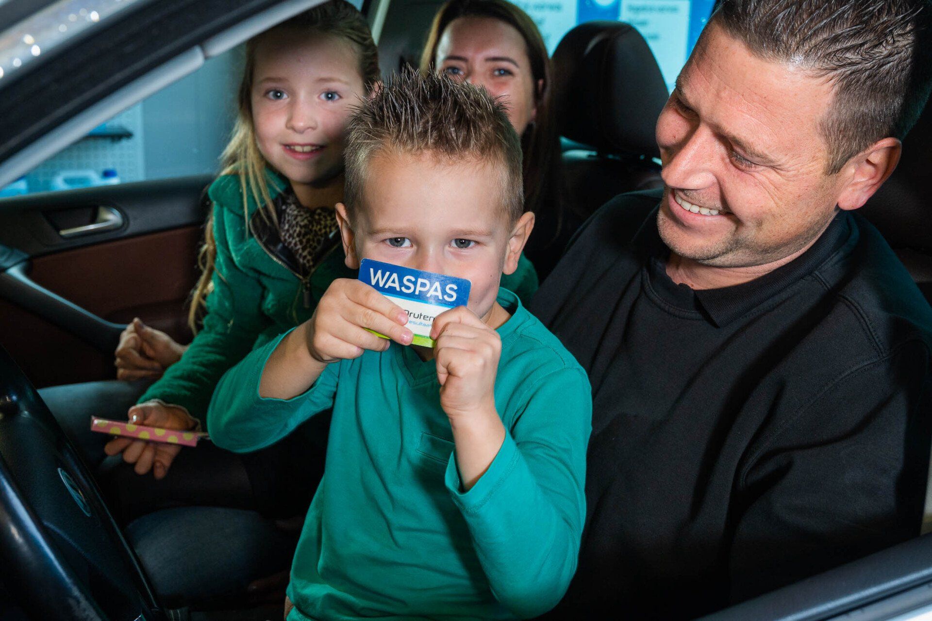Een man en twee kinderen zitten in een auto.