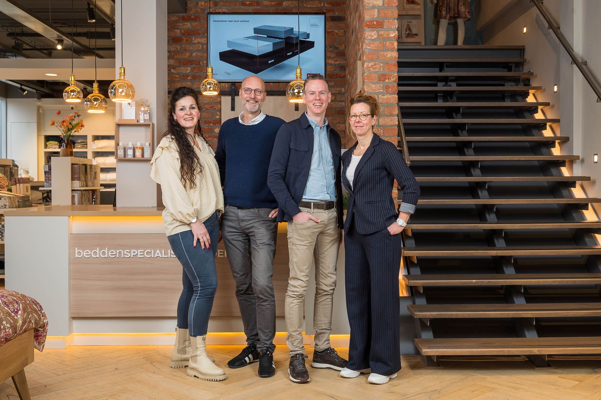 Een groep mensen poseert voor een foto voor een trap.