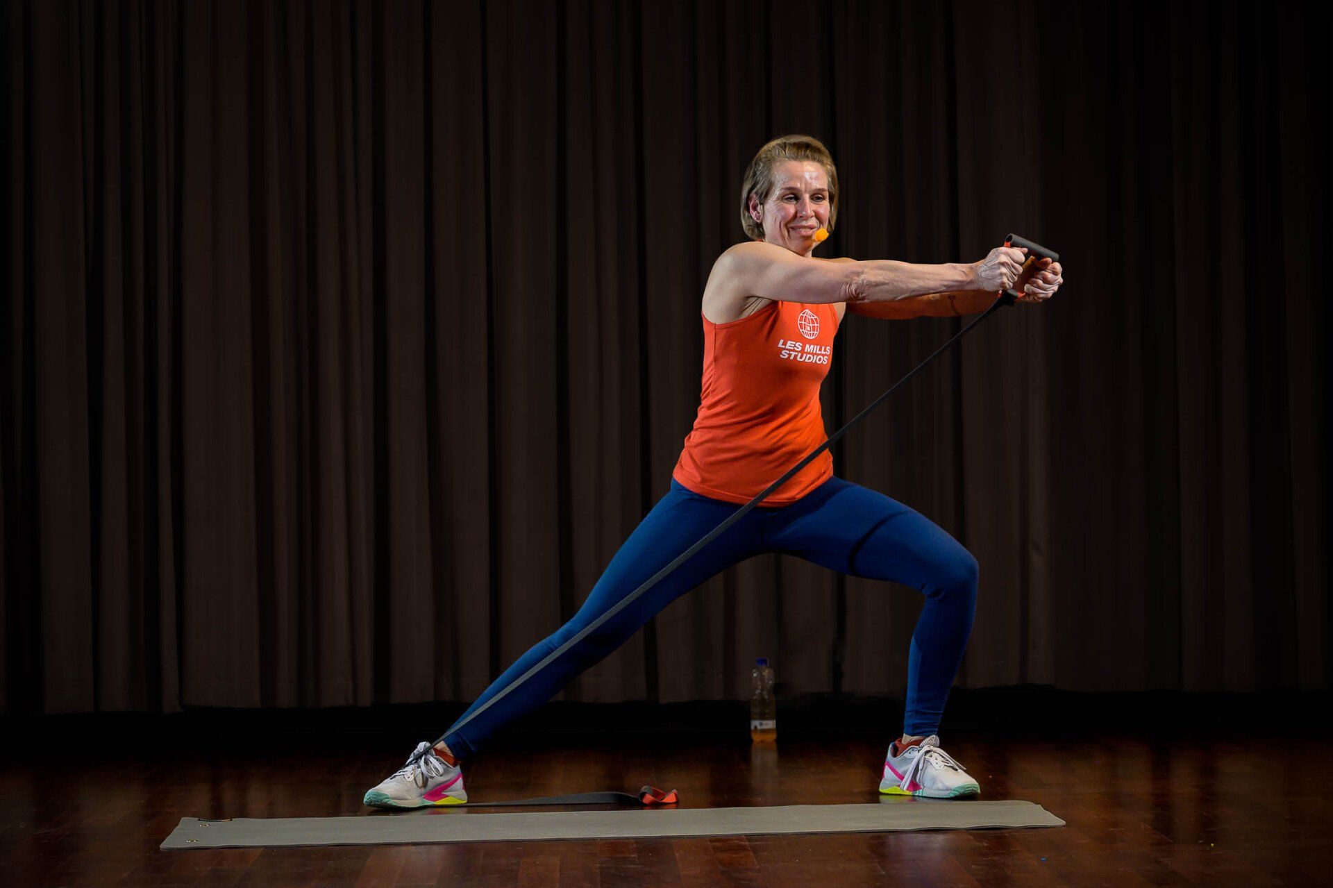 Een vrouw staat op een yogamat met een weerstandsband om haar middel.